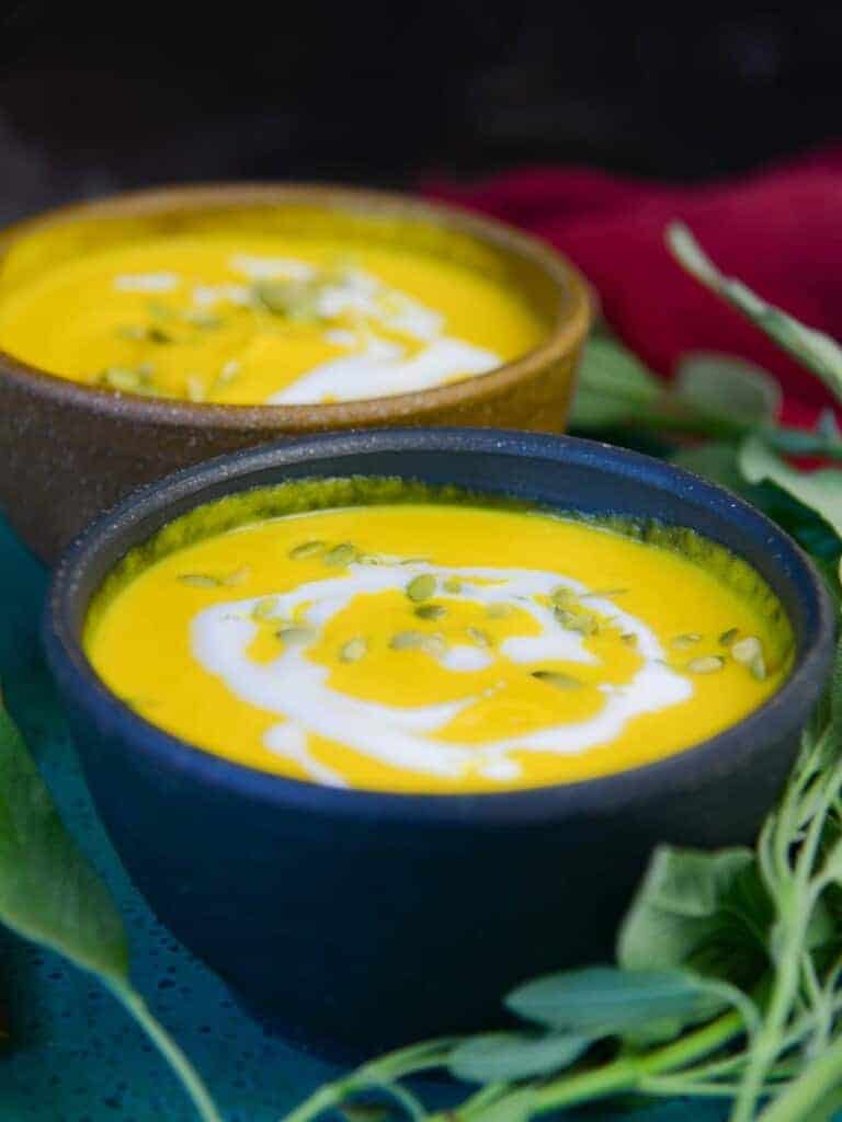 Two bowls of butternut squash soup with sage and coconut cream