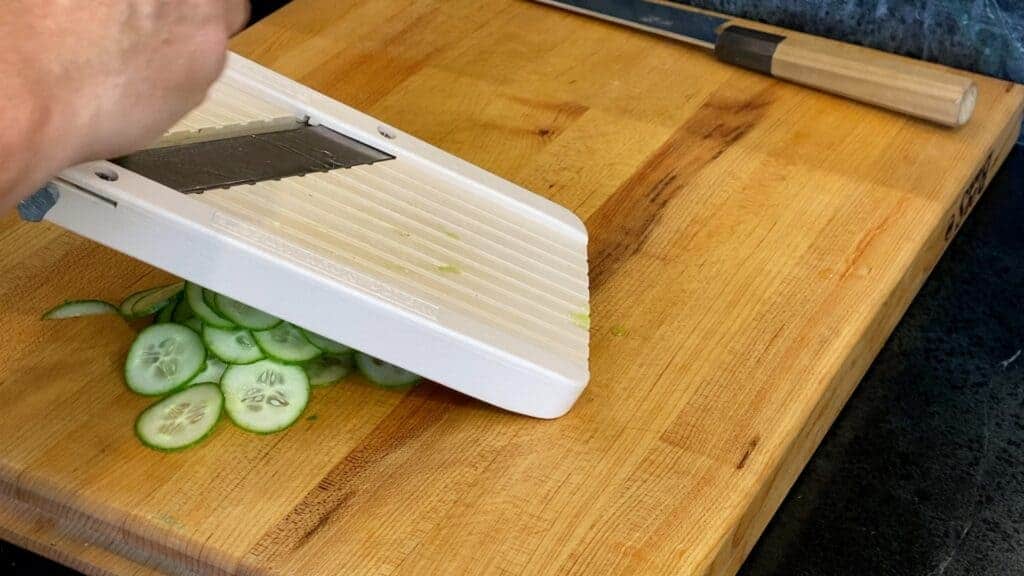Slicing cucumber with a mandoline slicer for asain cucumber salad.