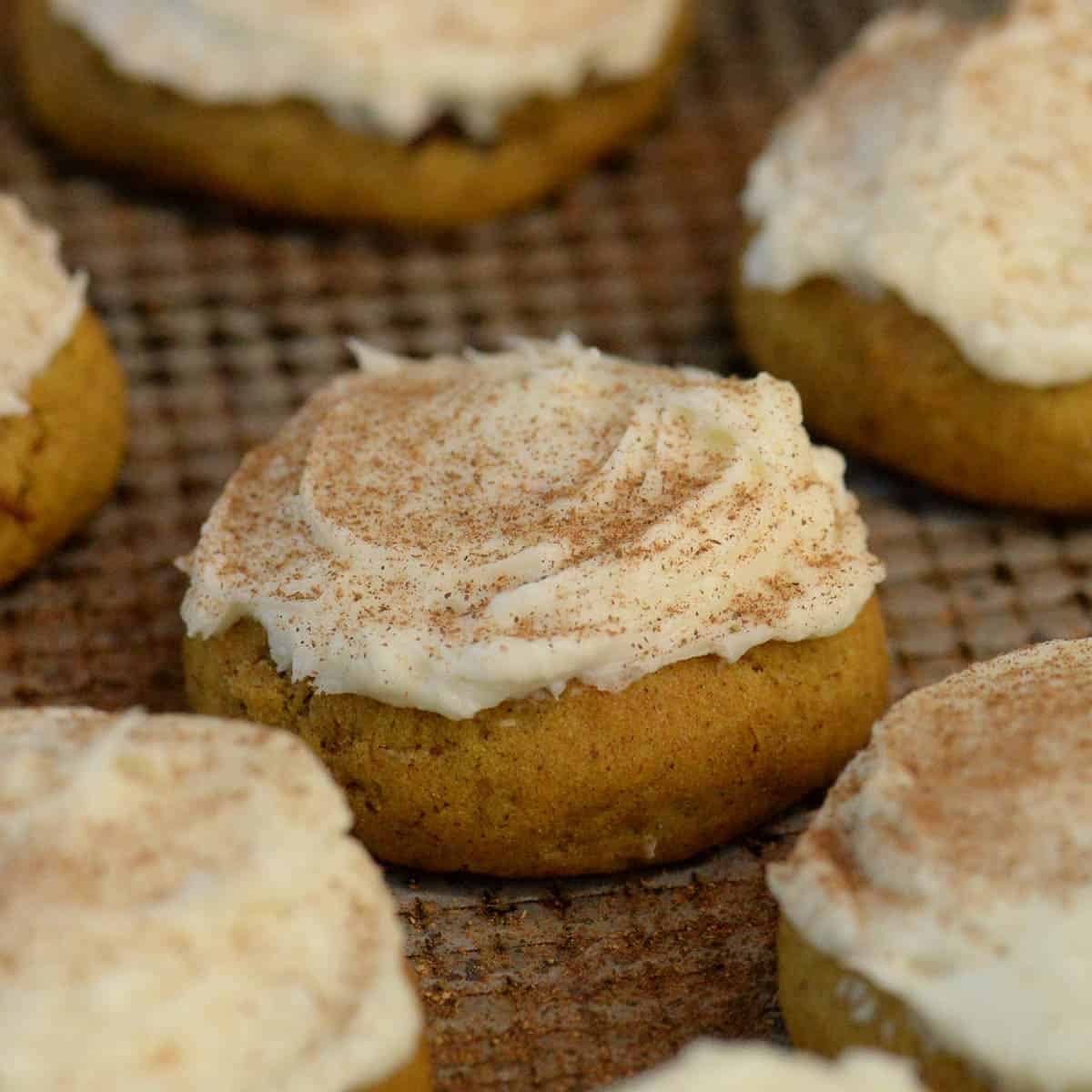 pumpkin cookies with cream cheese frosting on a metal baking sheet