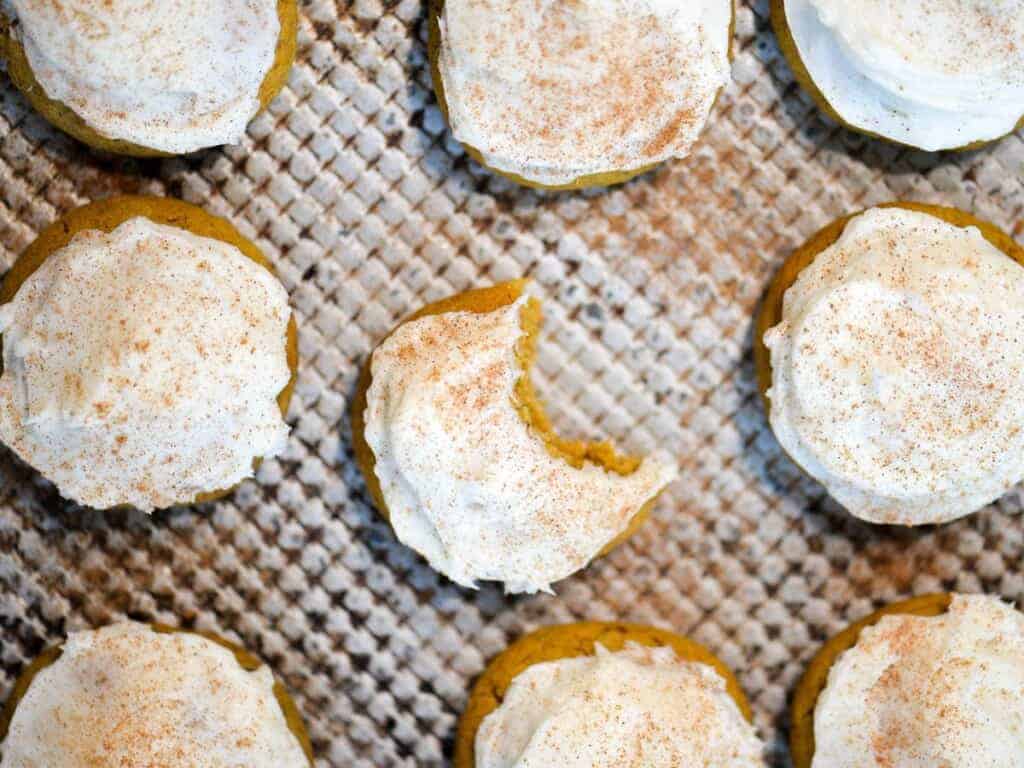 A baking sheet of pumpkin cookies frosted with cream cheese frosting.