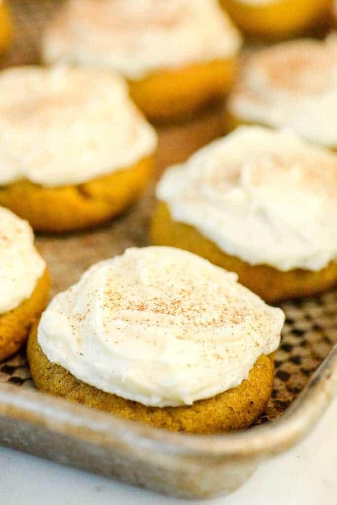 pumpkin cookies with cream cheese frosting on a baking sheet