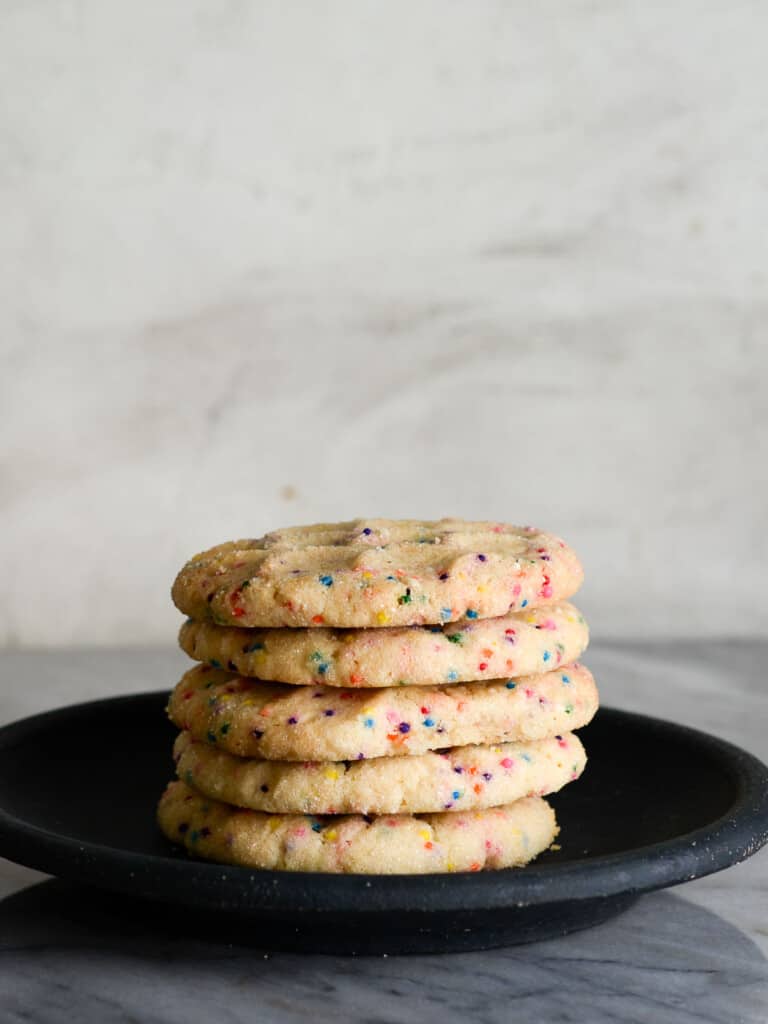 a stack of sugar cookies on a black plate