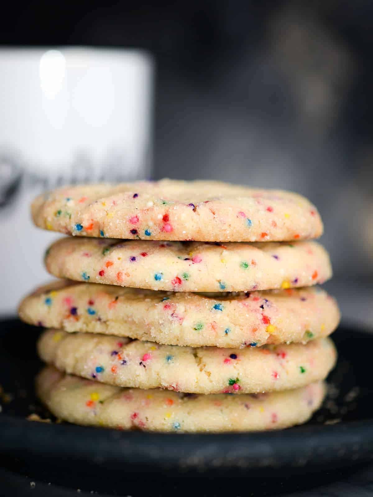 a stack of rainbow sprinkle sugar cookies on a plate