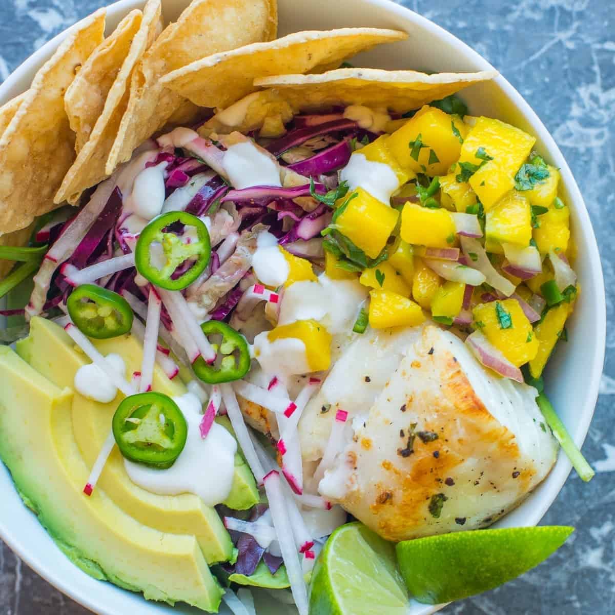 fish taco bowl with mango salsa and taco slaw. served with fresh avocado