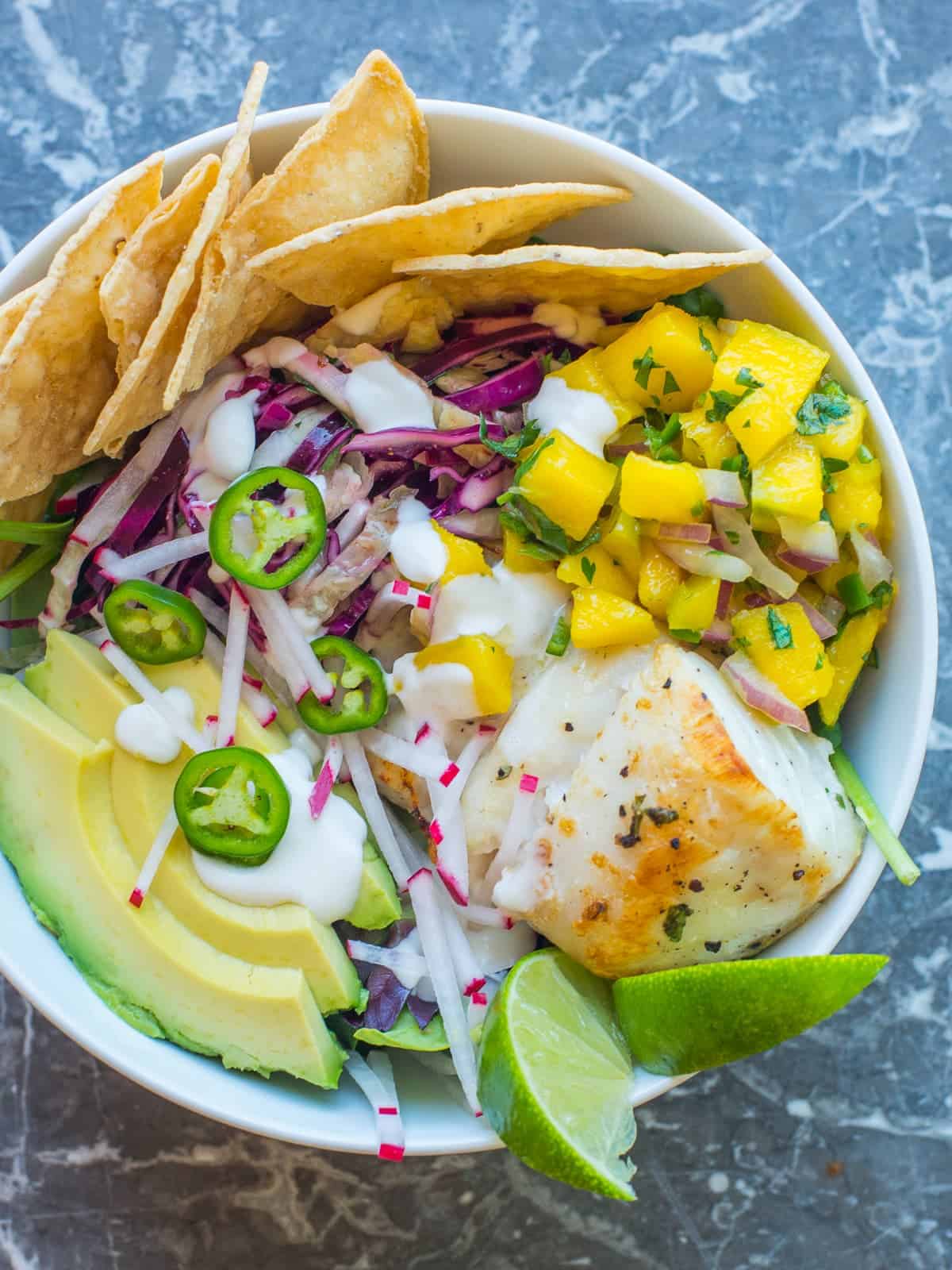 fish taco bowl with mango salsa and taco slaw. served with fresh avocado