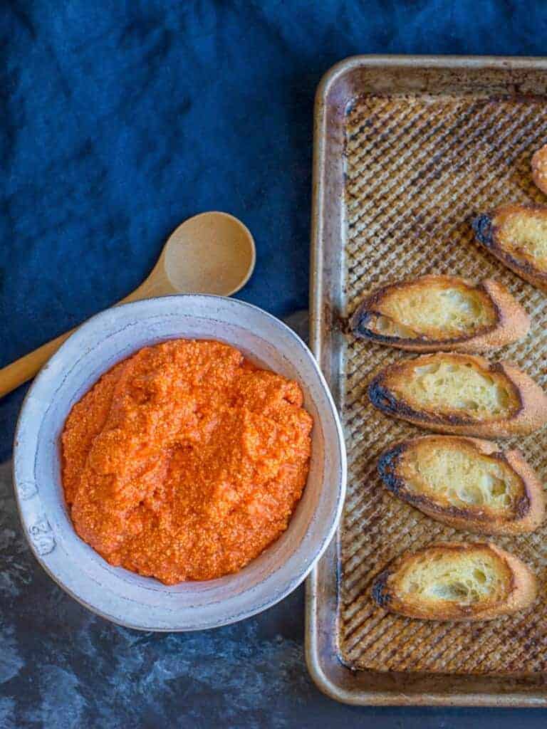 roasted red pepper and feta dip in a bowl served with crostini