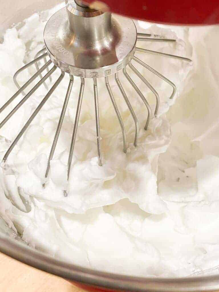 Keto marshmallows being whipped in a stand mixture fitted with a whisk attachment. 