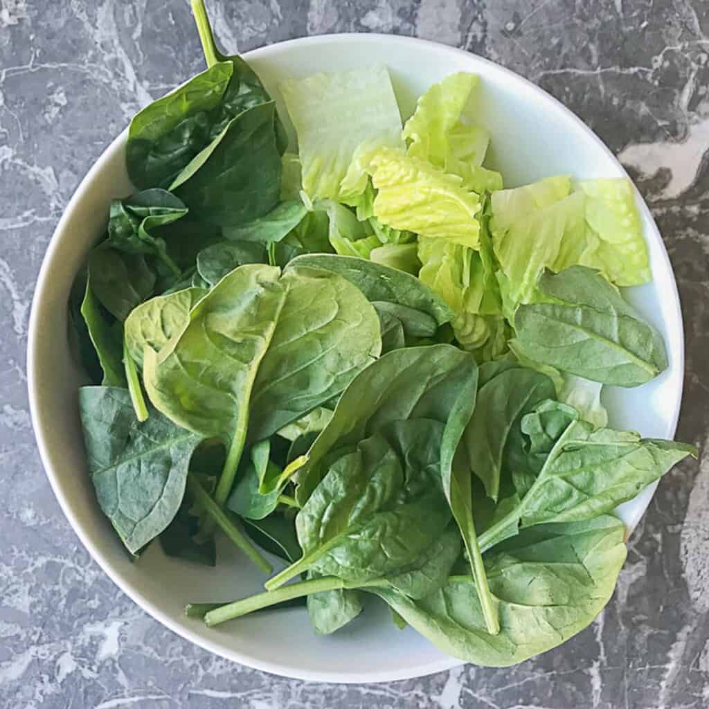 white bowl with a handful of lettuce and spinach