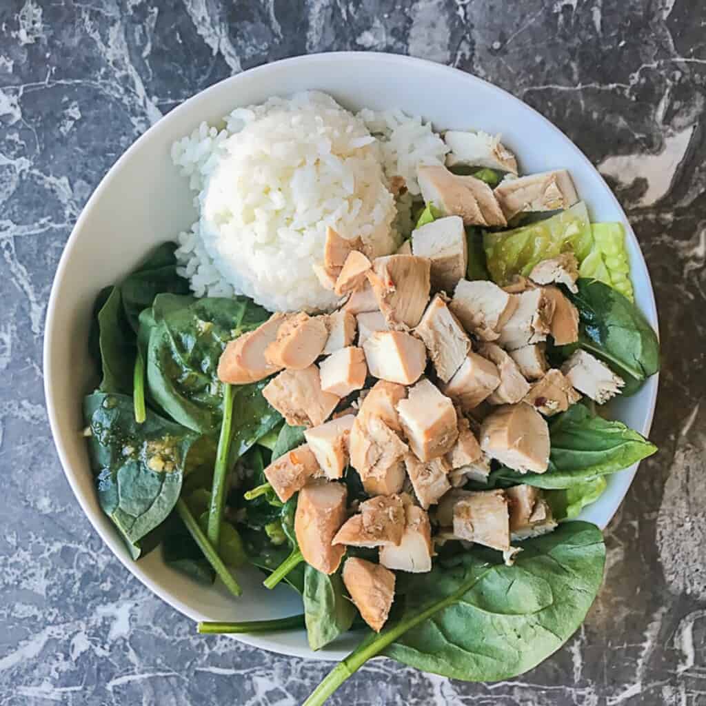 lettuce and spinach with sesame ginger dressing and a scoop of sushi rice and teriyaki chicken