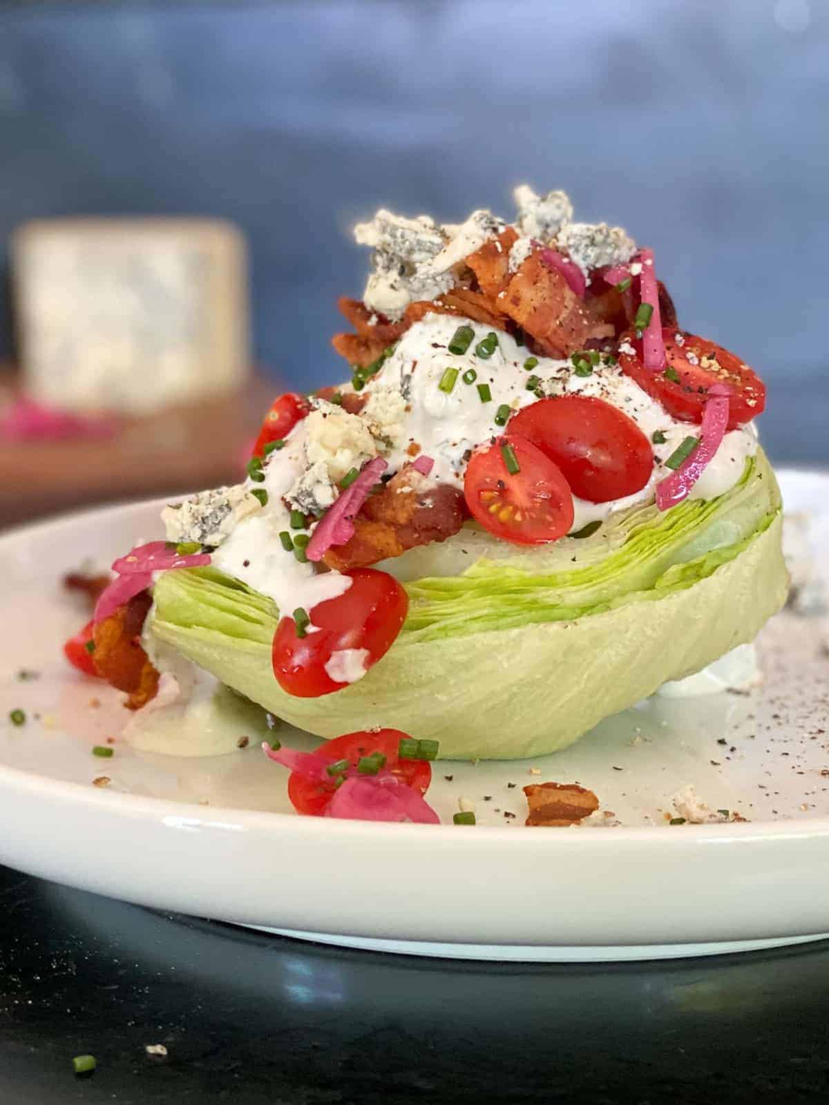 the perfect wedge salad. Cool, crisp iceberg lettuce topped with homemade blue cheese dressing, crispy bacon, fresh tomatoes and chives.