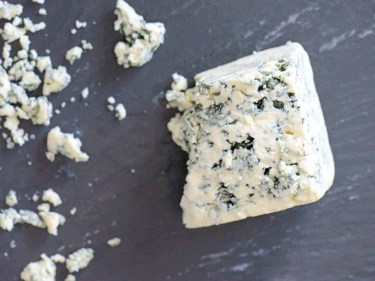 crumbled dainish blue cheese on a black cheeseboard