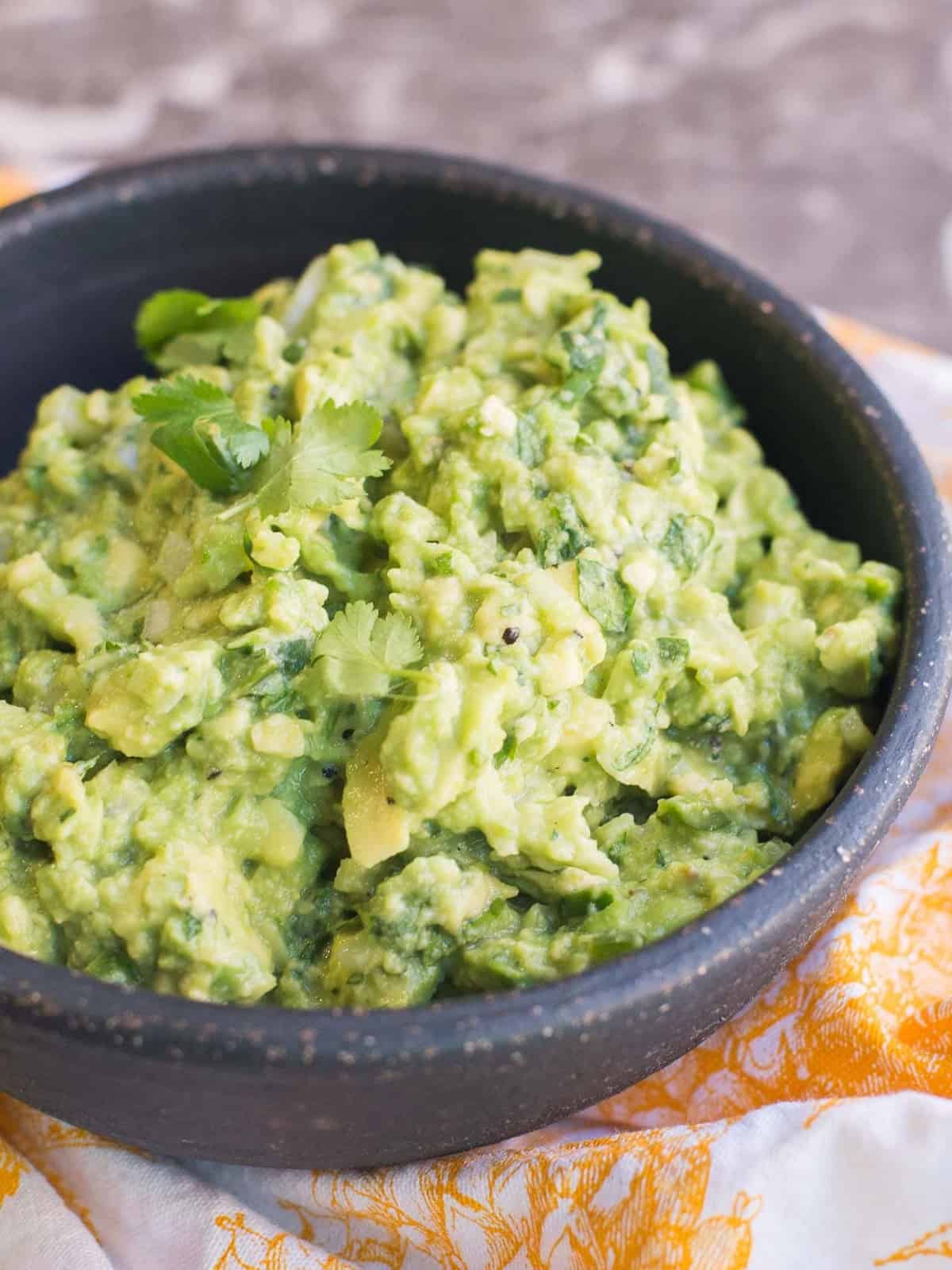 quick and easy guacamole recipe in a back stone bowl