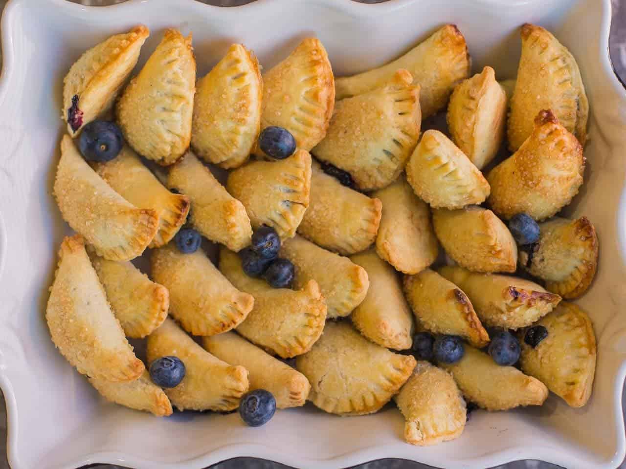 a finished tray of blueberry hand pies in a black and white dish