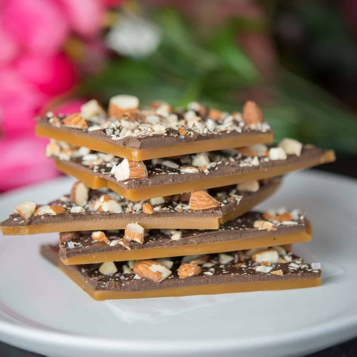 a stack of homemade butter toffee with a layer of dark chocolate and roasted almonds.