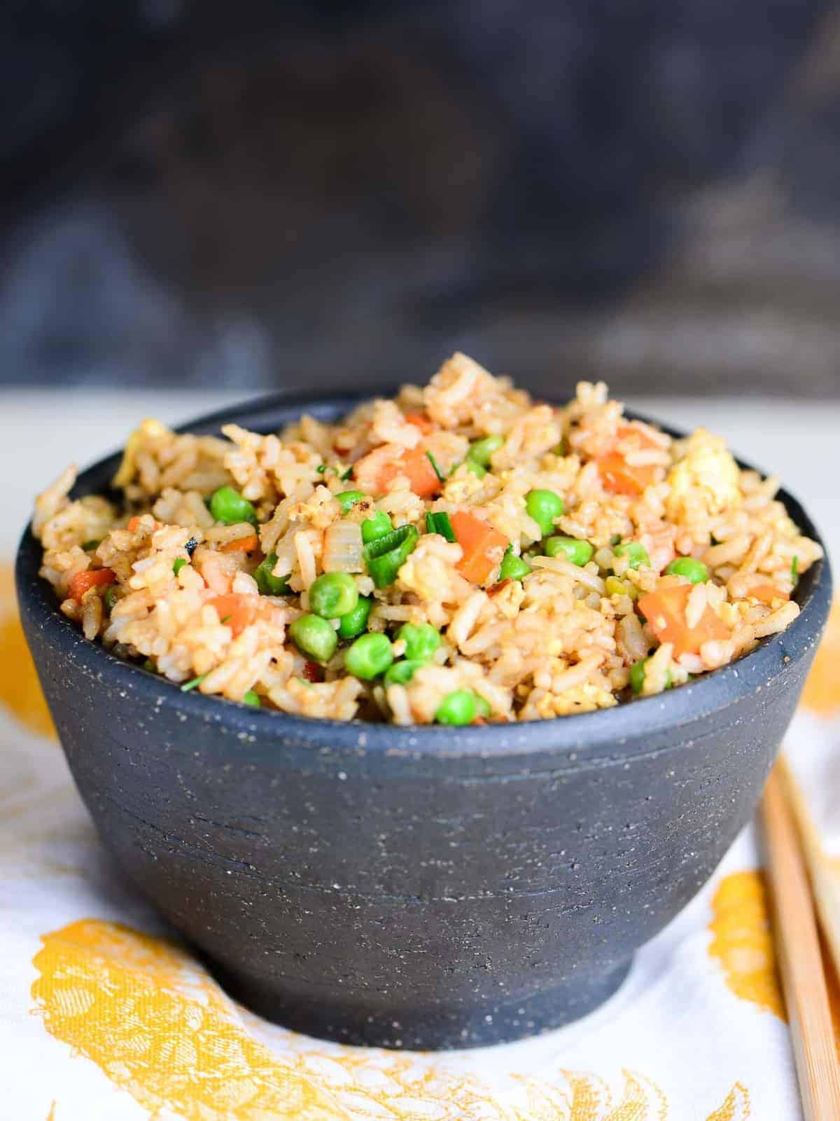 take out style fried rice with chopsticks in a black bowl
