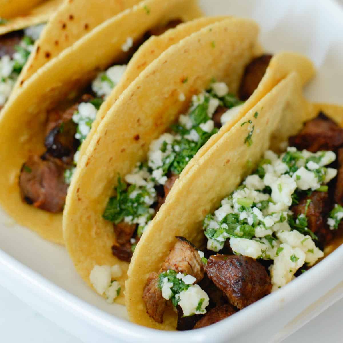 carne asada tacos topped with cilantro and lime and cotija cheese