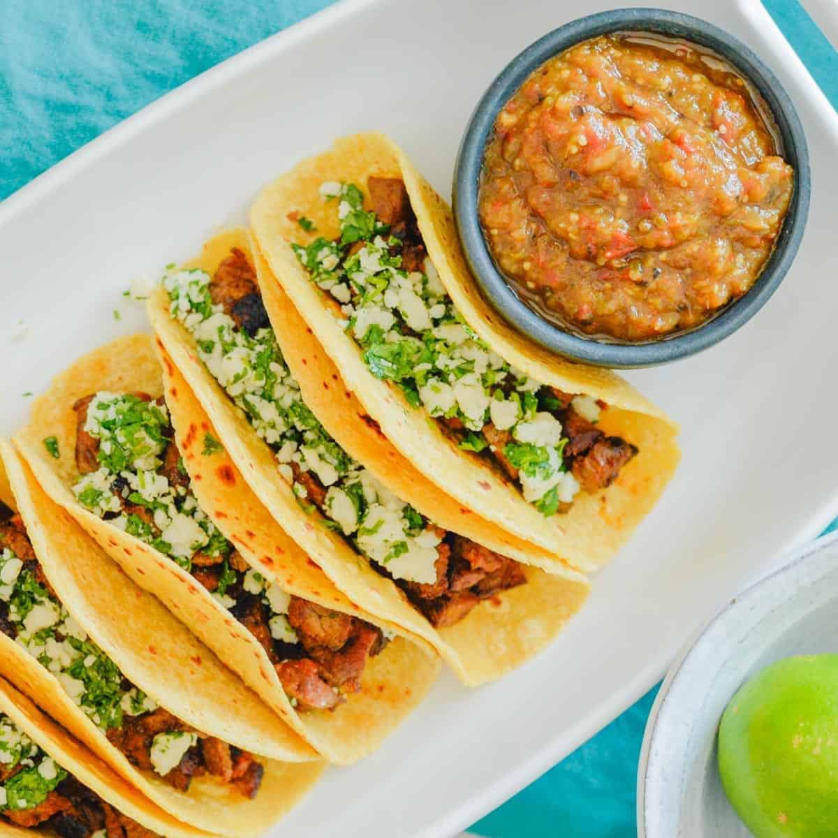 carne asada tacos with pepper sauce in a white platter