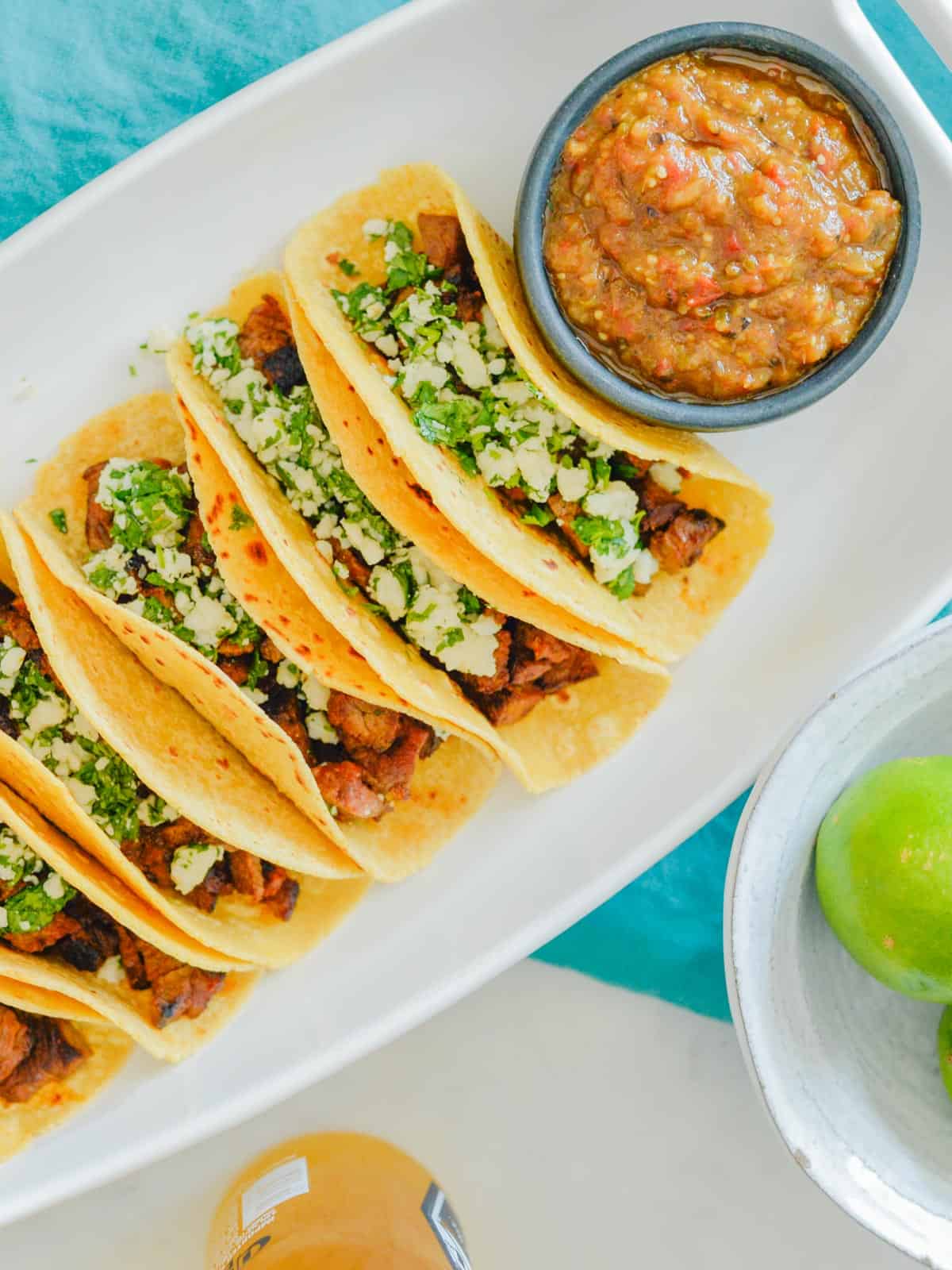 carne asada tacos with pepper sauce in a white platter