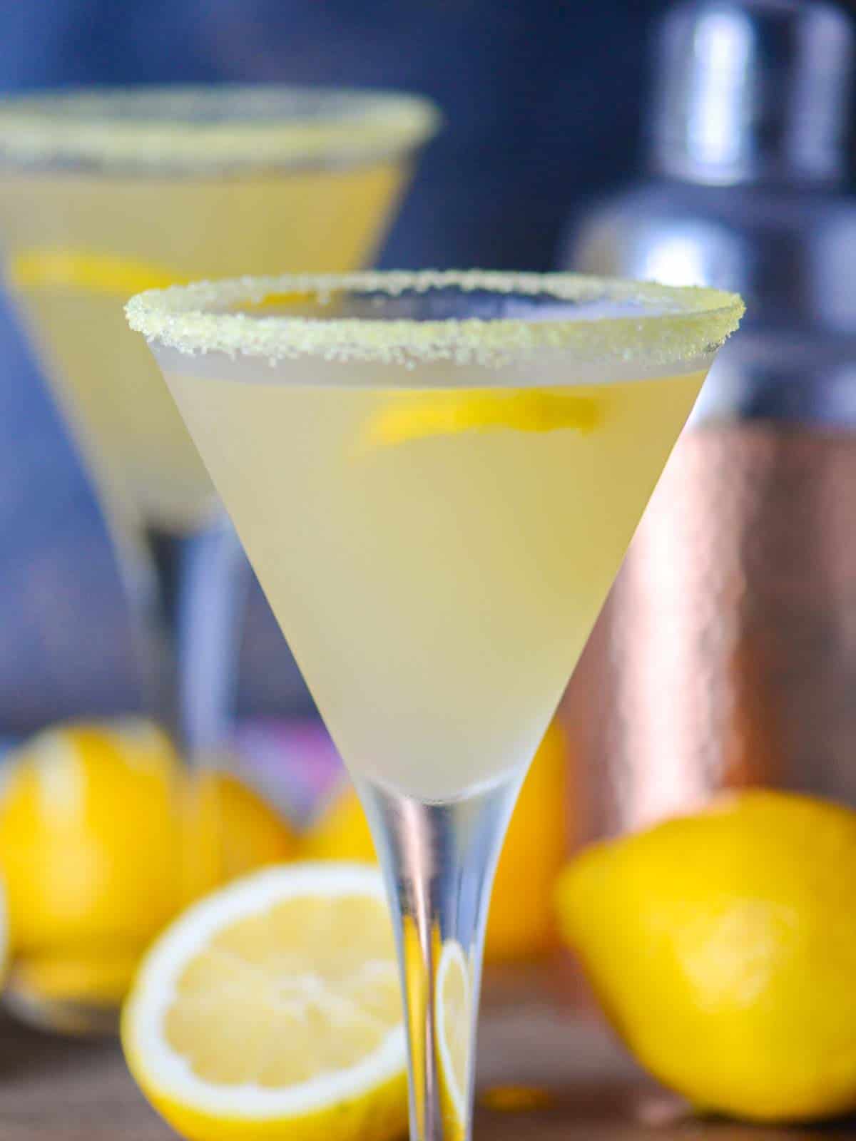 two lemon drop martinis in a frosted glasses with a copper cocktail shaker
