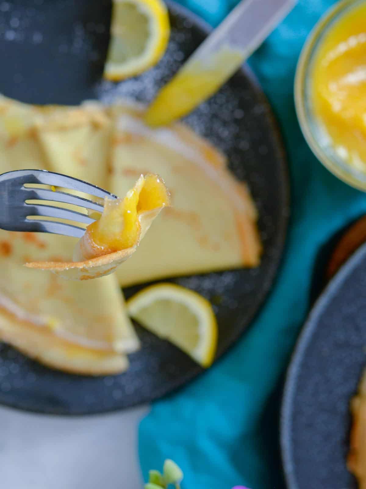 bite of crepe on a fork with lemon curd