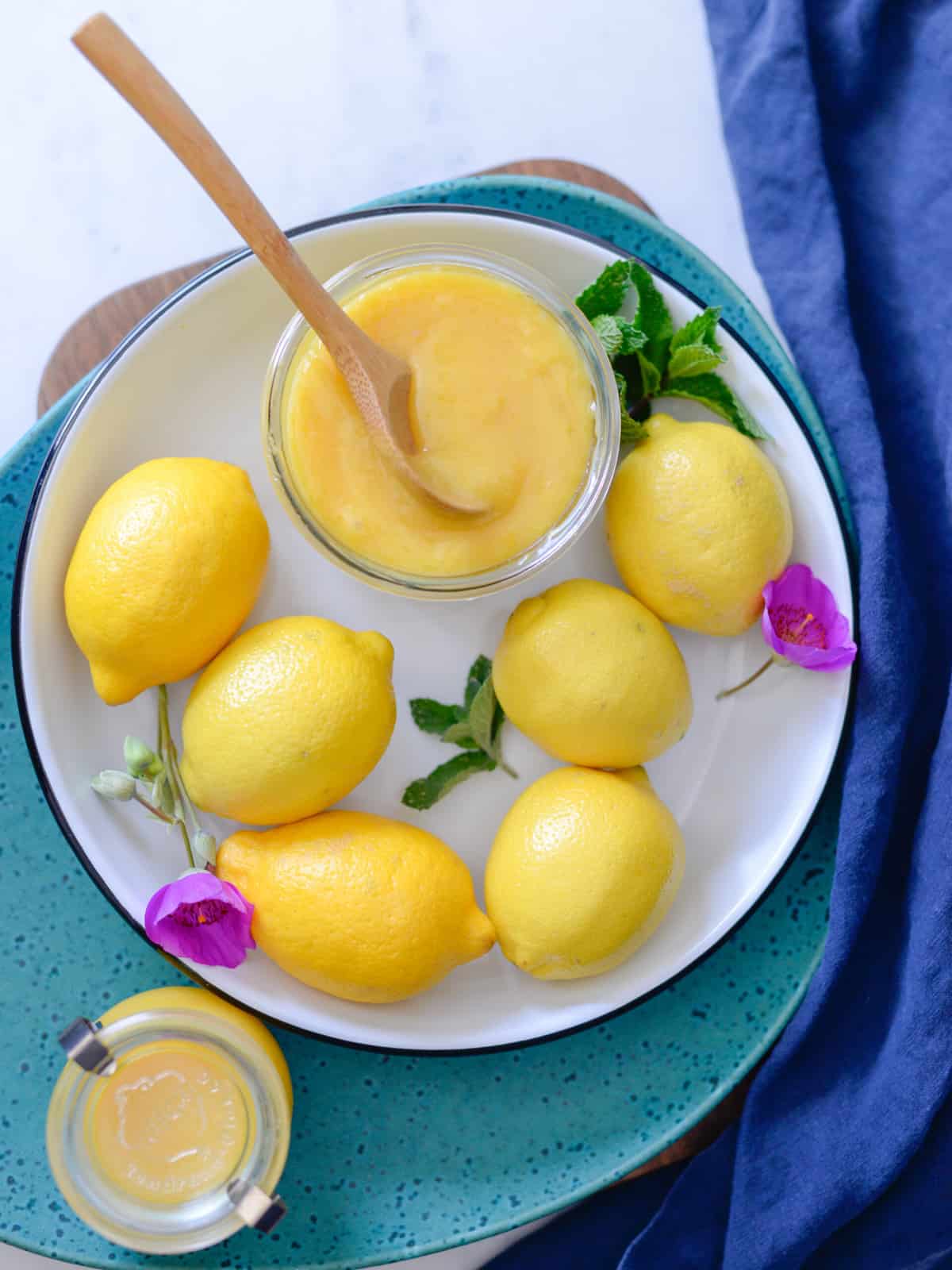 lemon curd pictured with fresh lemons, mint and garden flowers