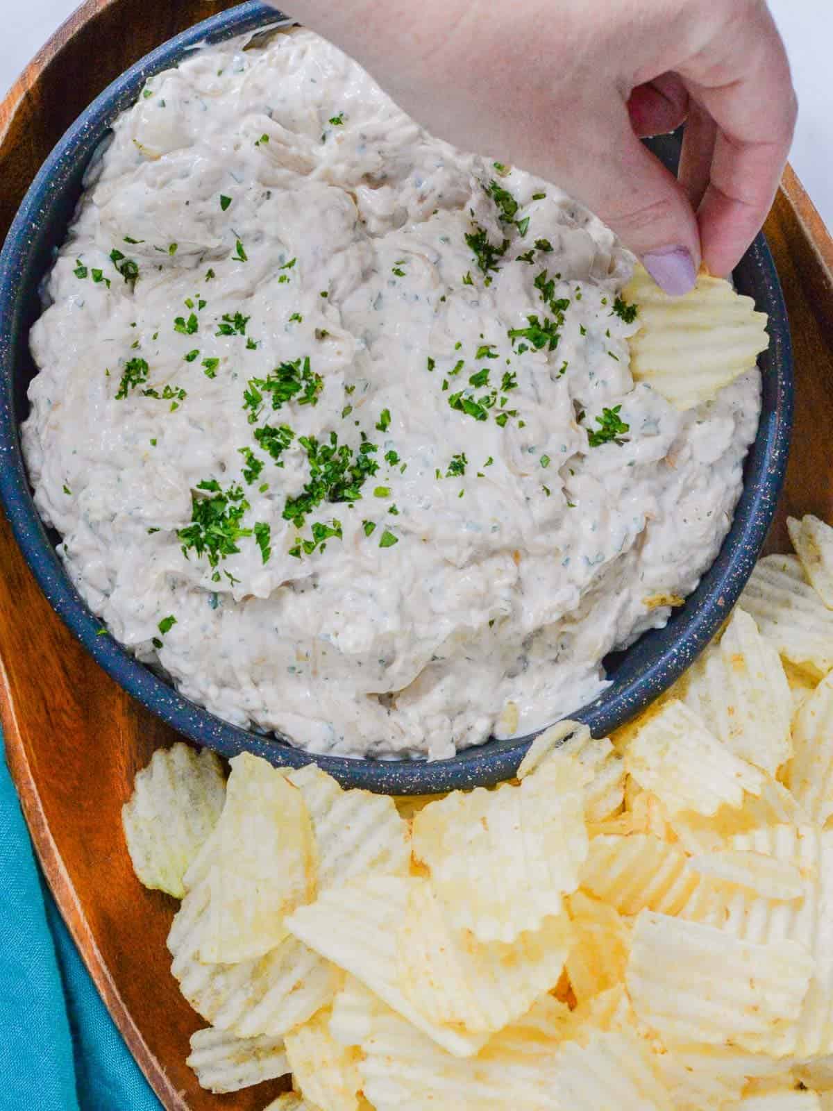 dipping a chip into sour cream and onion dip