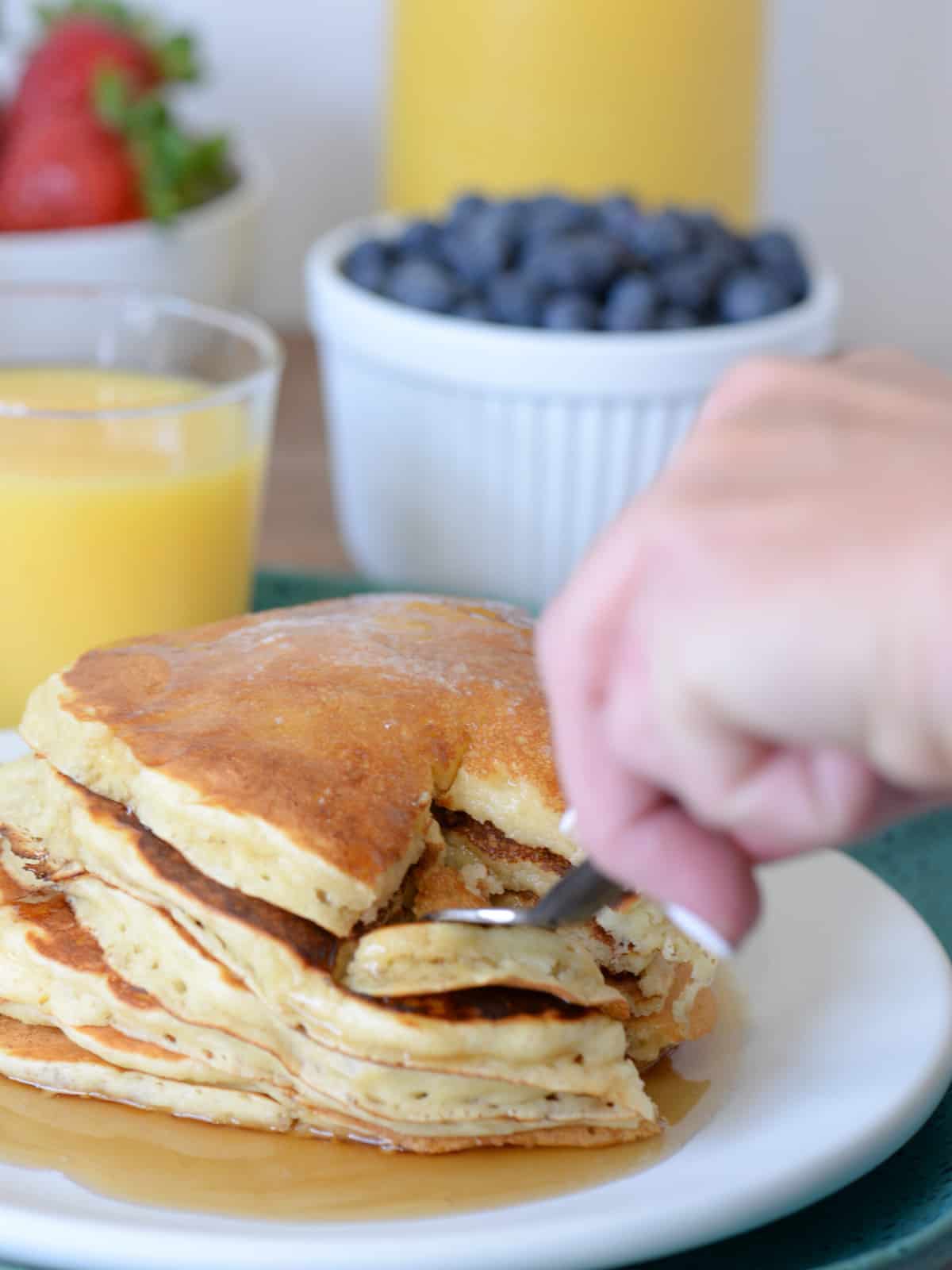 slicing a stack of buttermilk pancakes