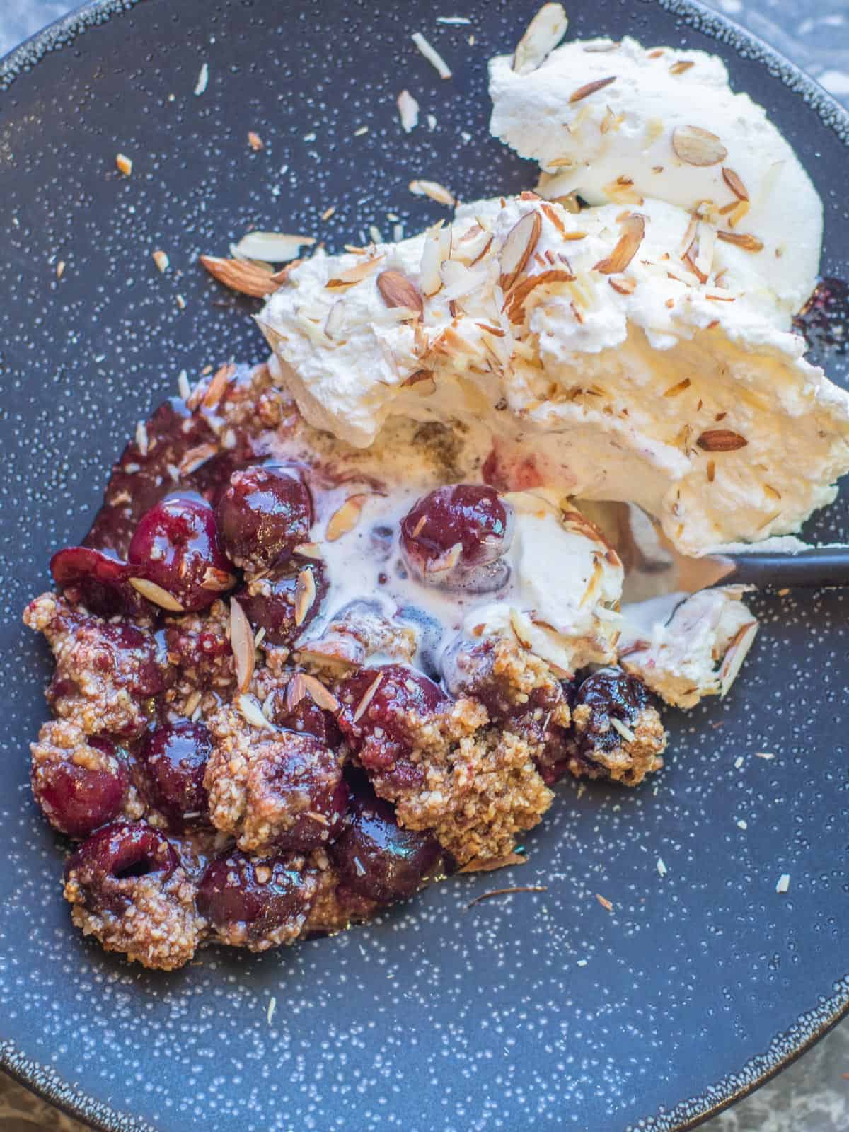 fresh baked cherry crumble with almond crisp topping and whipped cream