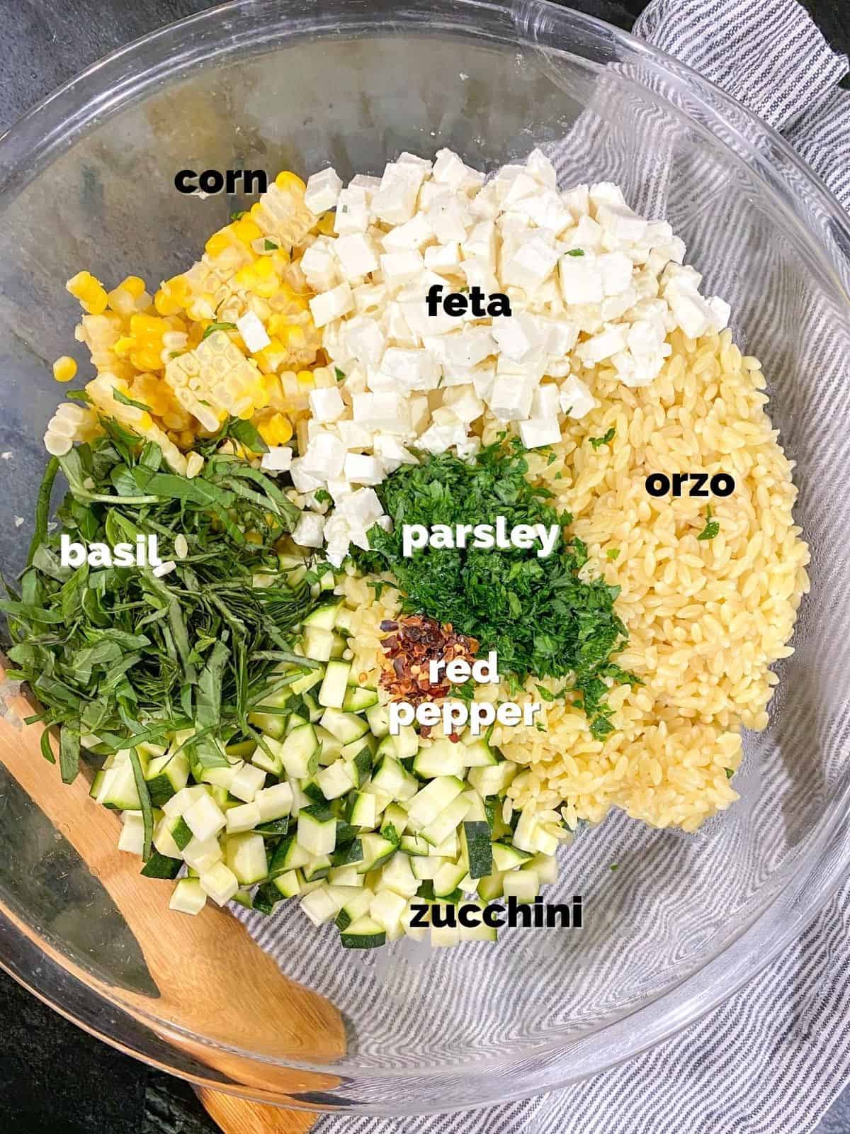 ingredients for the orzo salad with feta in a bowl ready to be tossed together