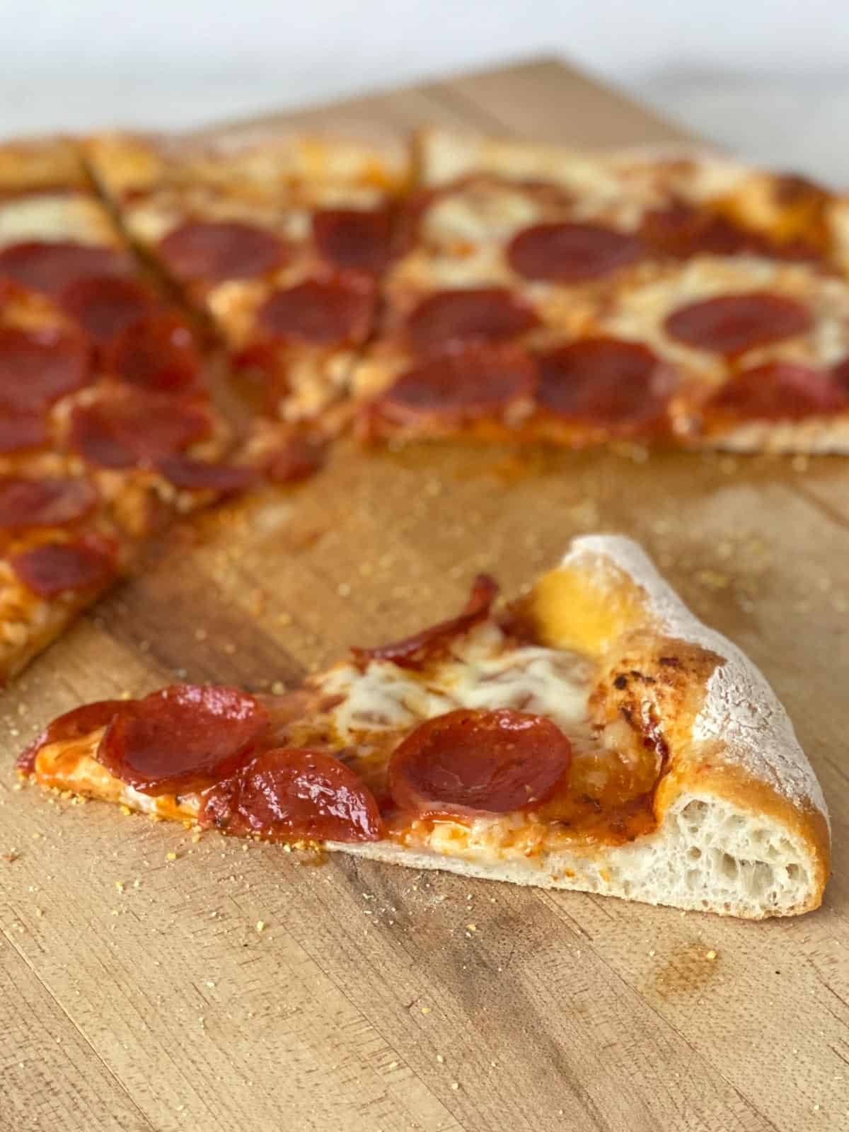 slice of homemade pizza crust topped with cheese and pepperoni