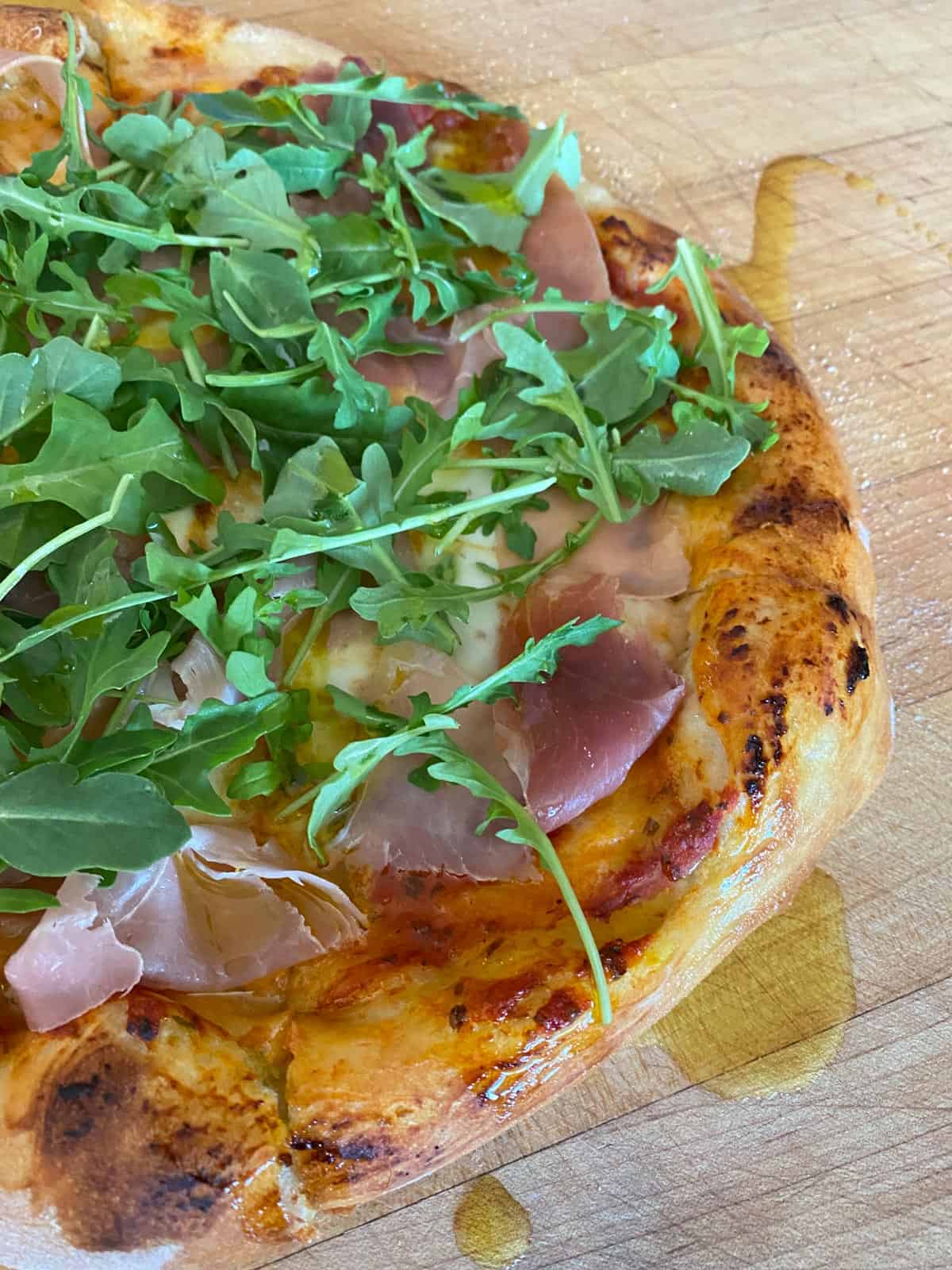 pizza dough recipe topped with prosciutto and arugula and olive oil