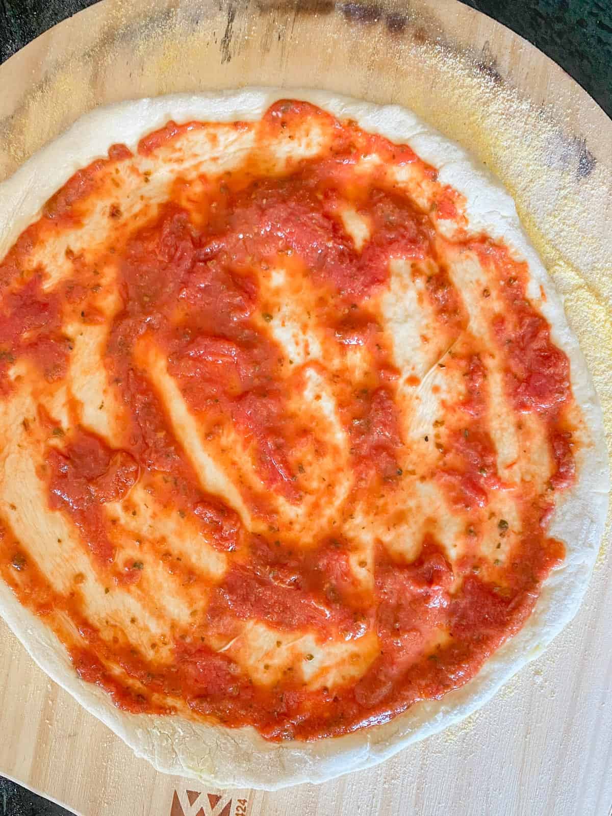 homemade pizza sauce on pizza dough