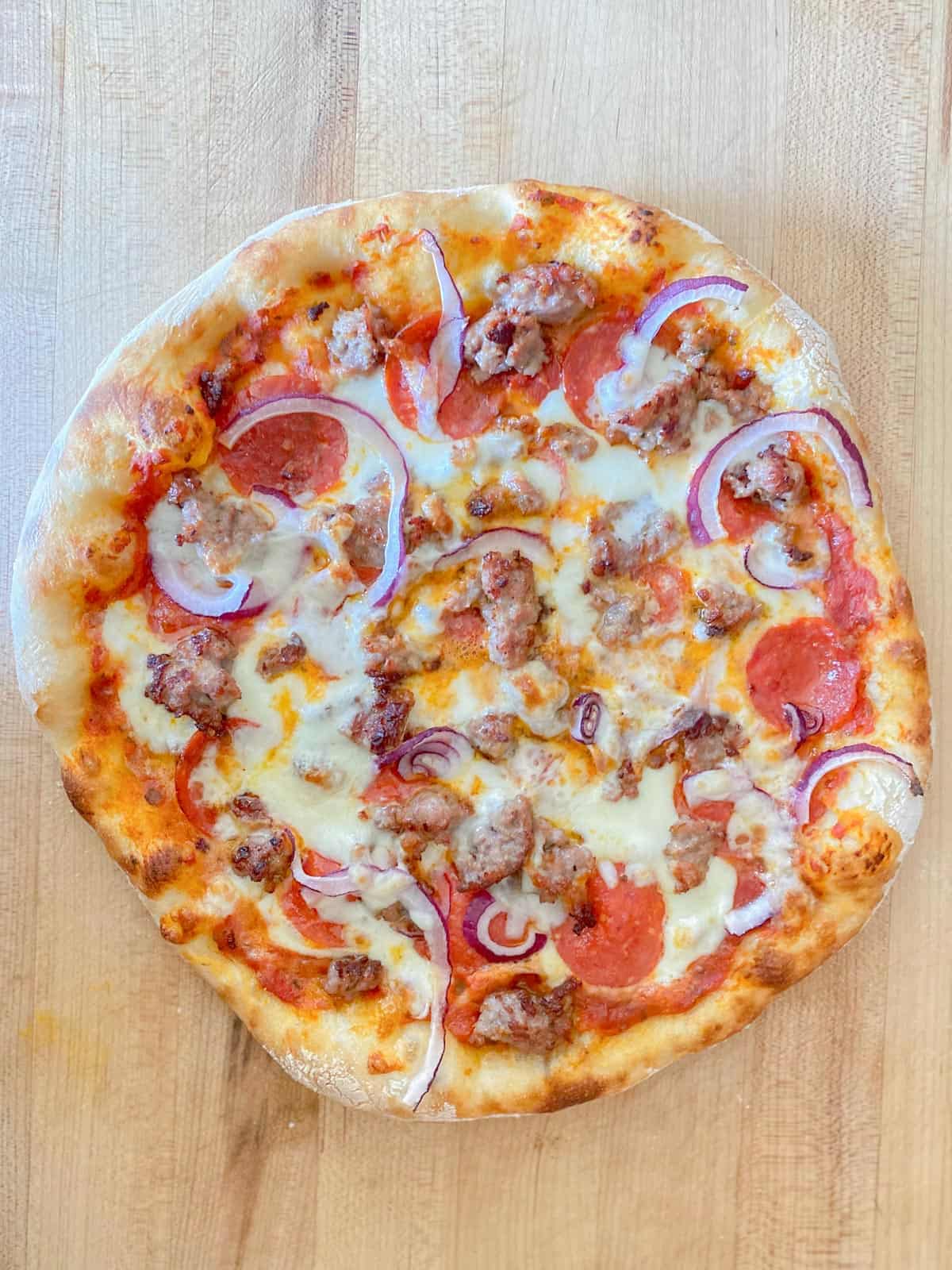 sausage and pepperoni pizza with onions made on homemade pizza dough