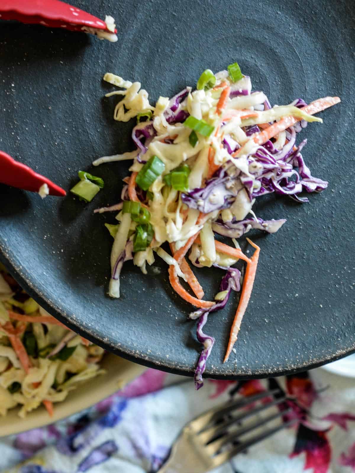 a black plate with a serving of  coleslaw