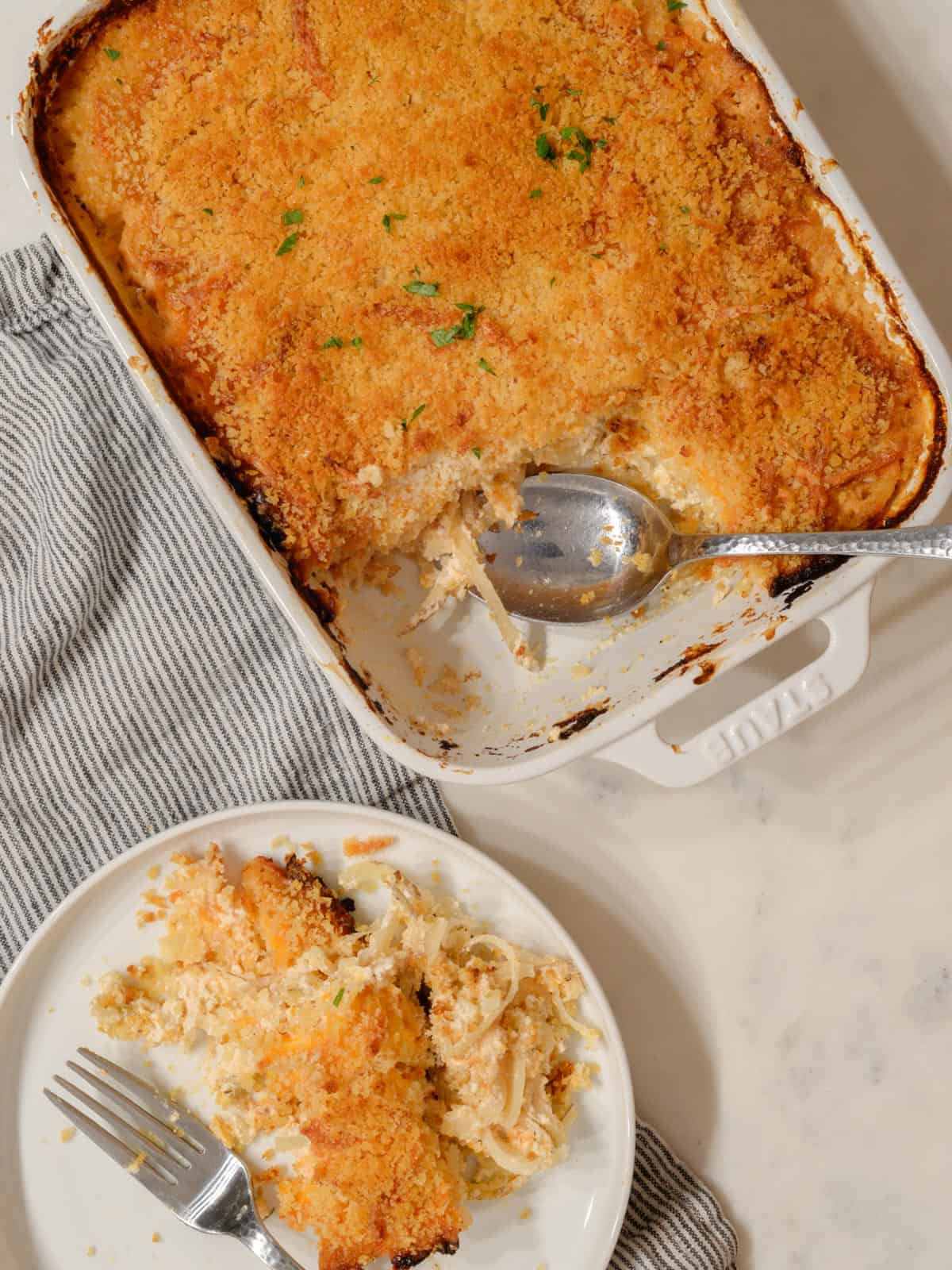 cheesy hashbrown casserole with bread crumb topping in a white baking dish