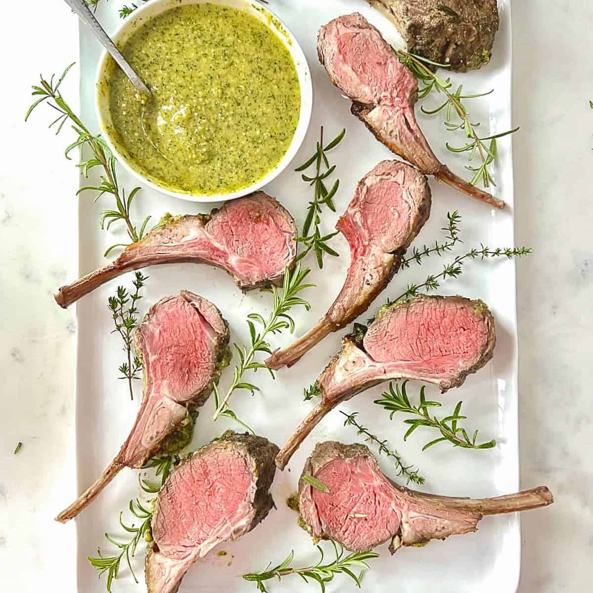 grilled rack of lamb, sliced and served on a platter with a mint pesto