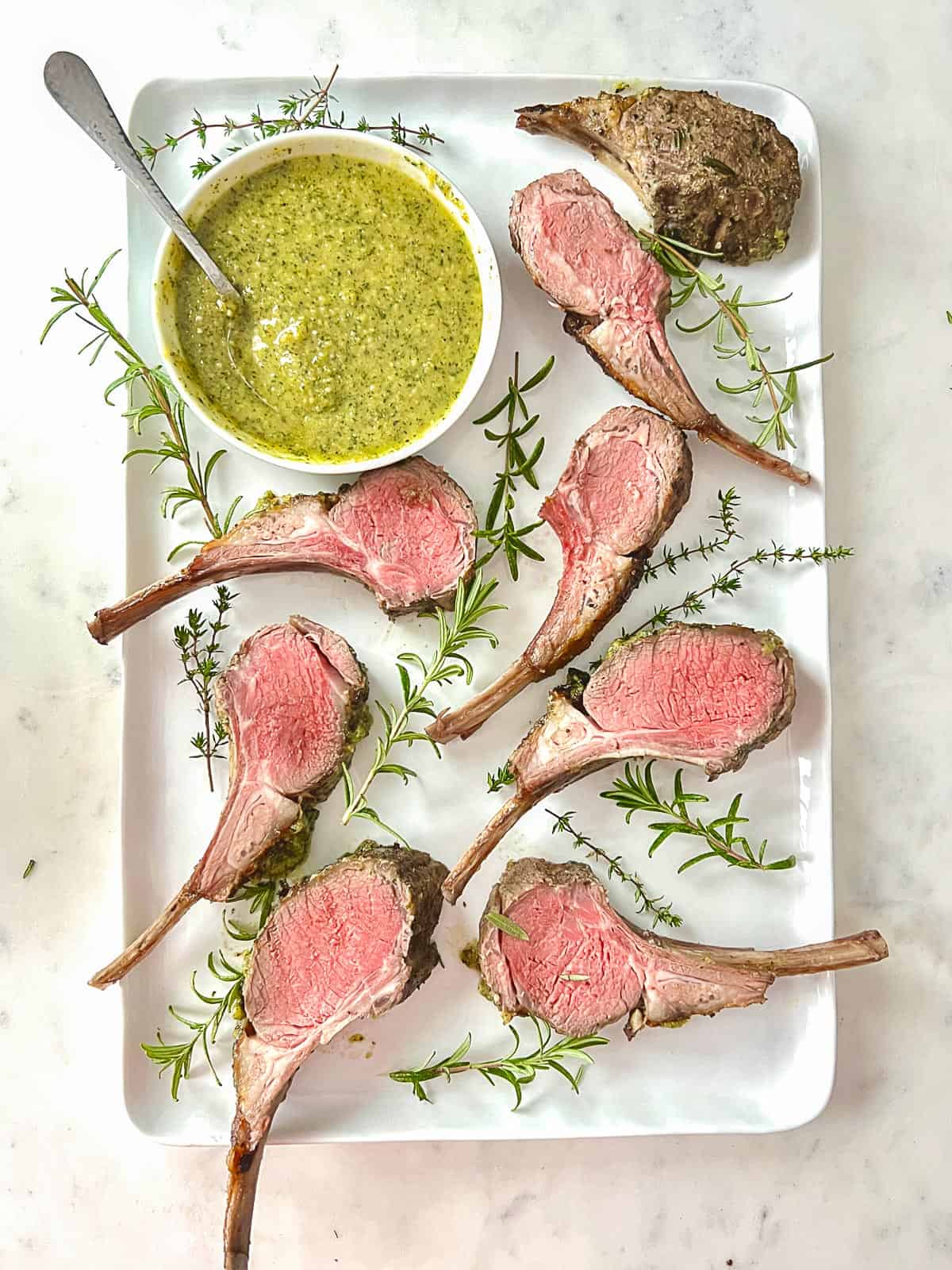 grilled rack of lamb, sliced and served on a platter with a mint pesto