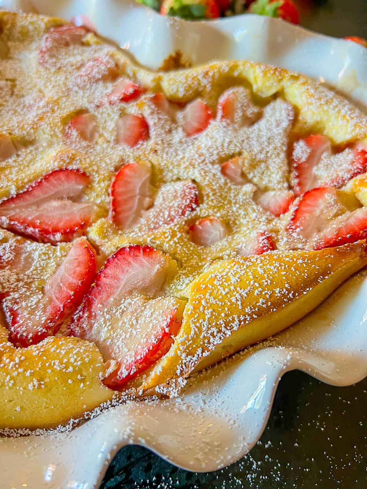 close up of a clafoutis made with strawberries and spinkled with powdered sugar