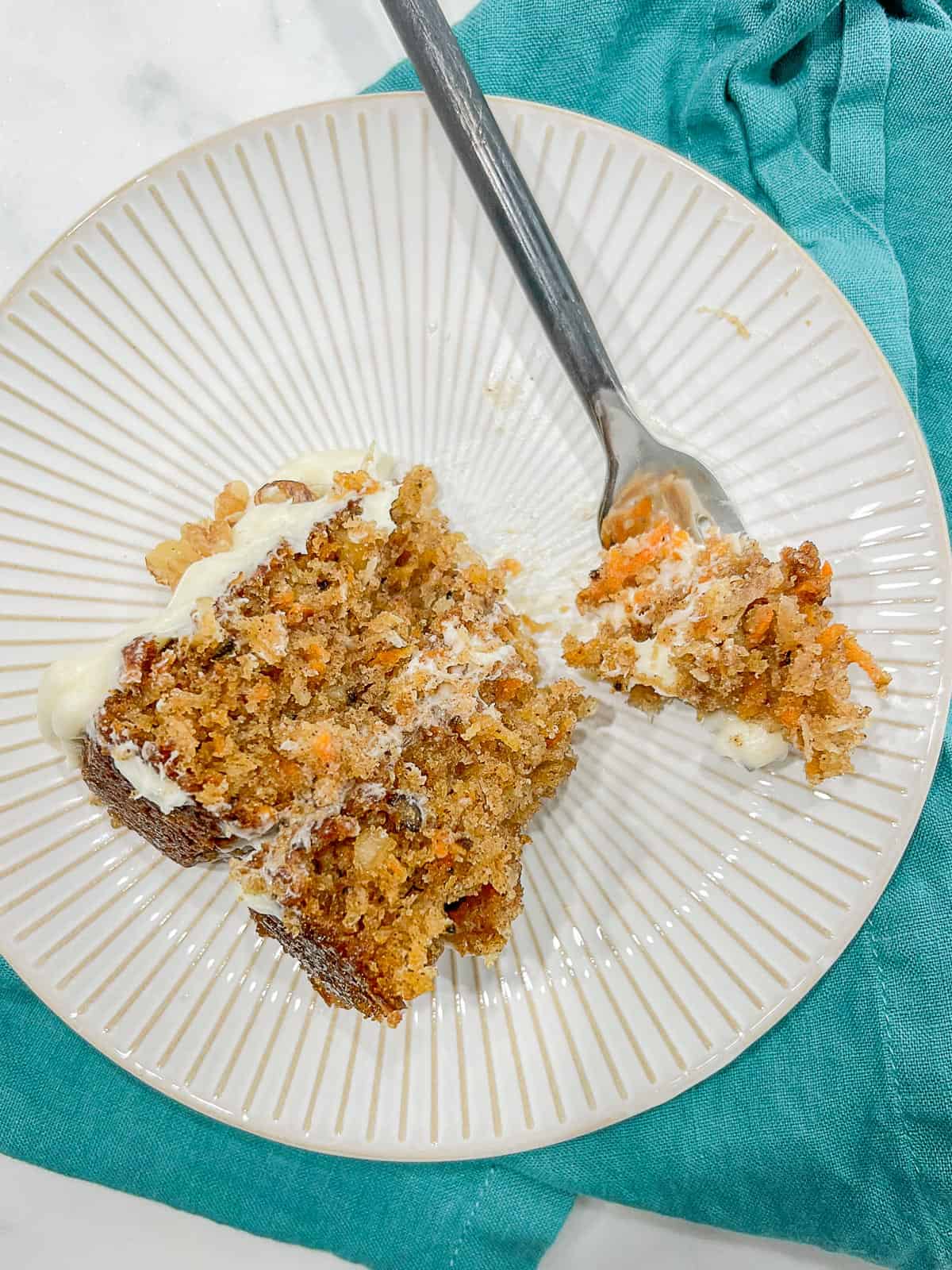 bite of the best carrot cake served on a white plate with a fork