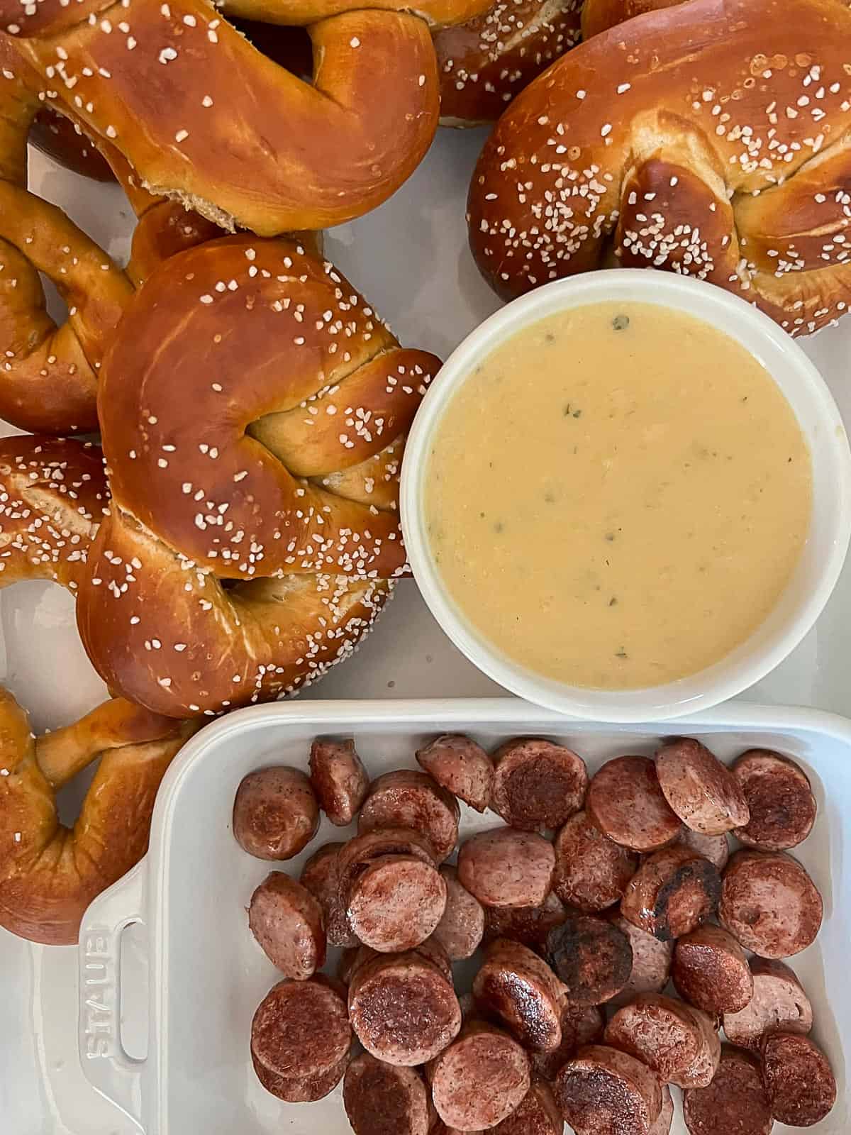 A beer cheese appetizer platter with sausage and pretzels for dipping