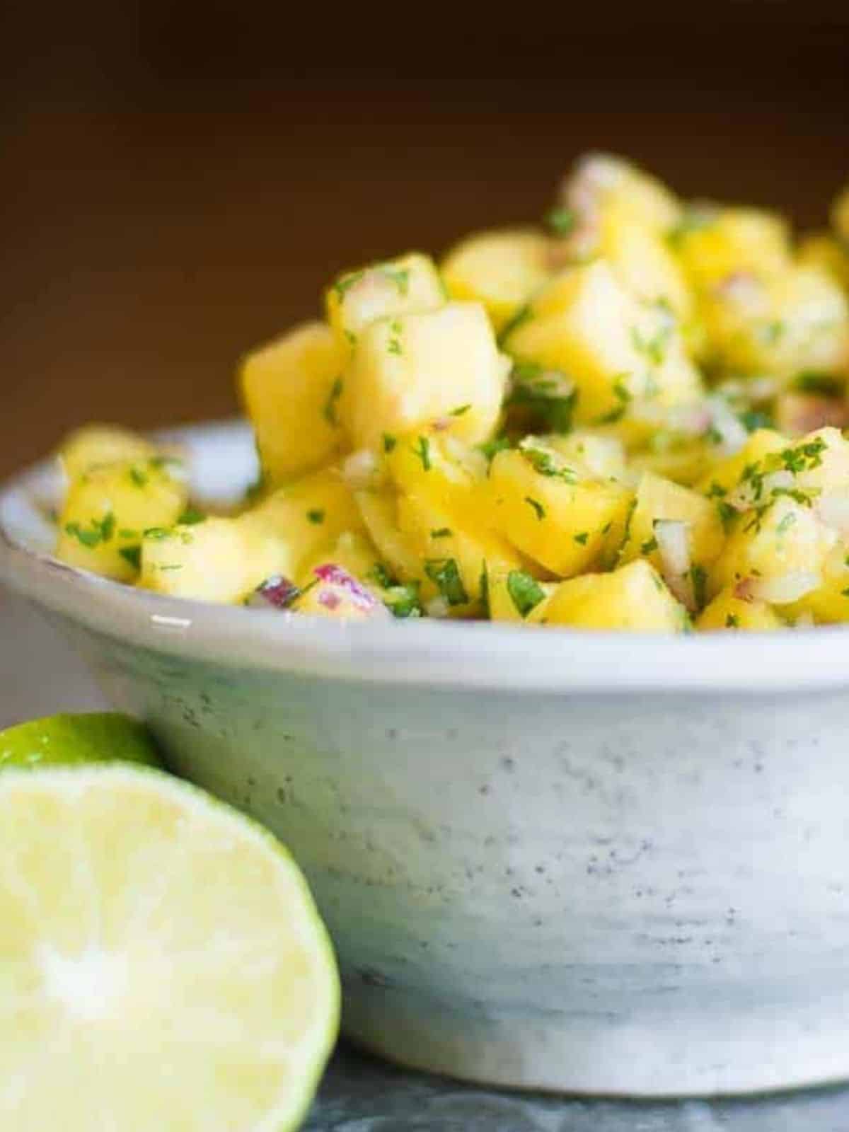 pineapple salsa in a white bowl with fresh cut limes