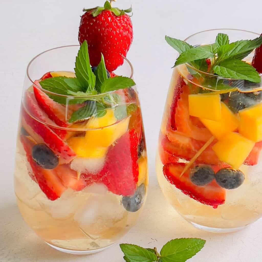 2 glasses of white wine sangria with berries and mangos