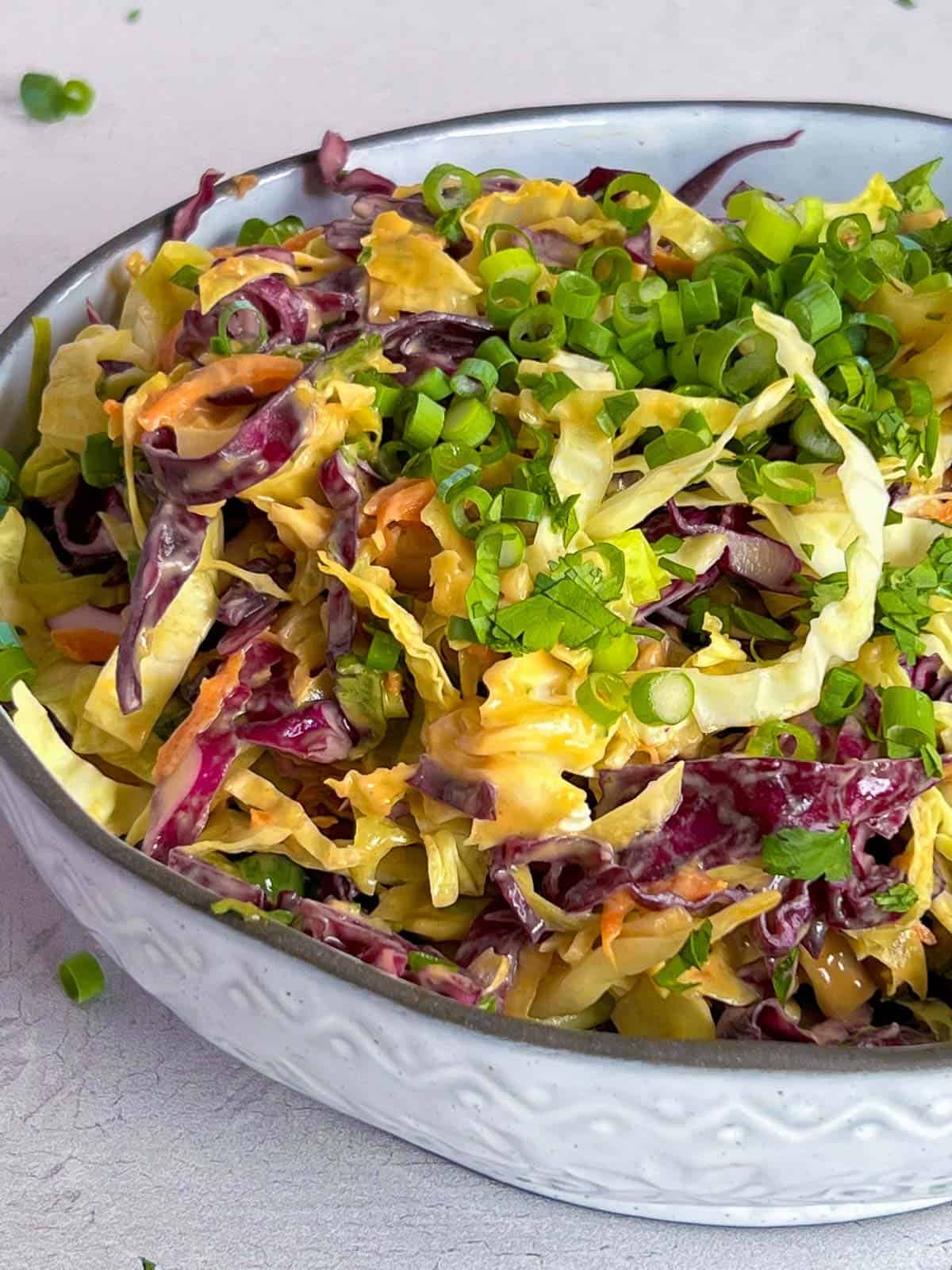 asian coleslaw with a peanut salad dressing in a white bowl