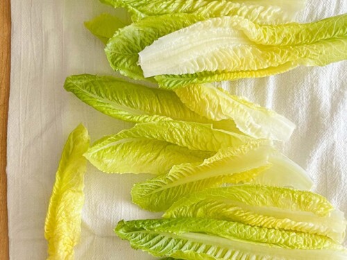 washed romaine hearts drying on a white flour sack towel