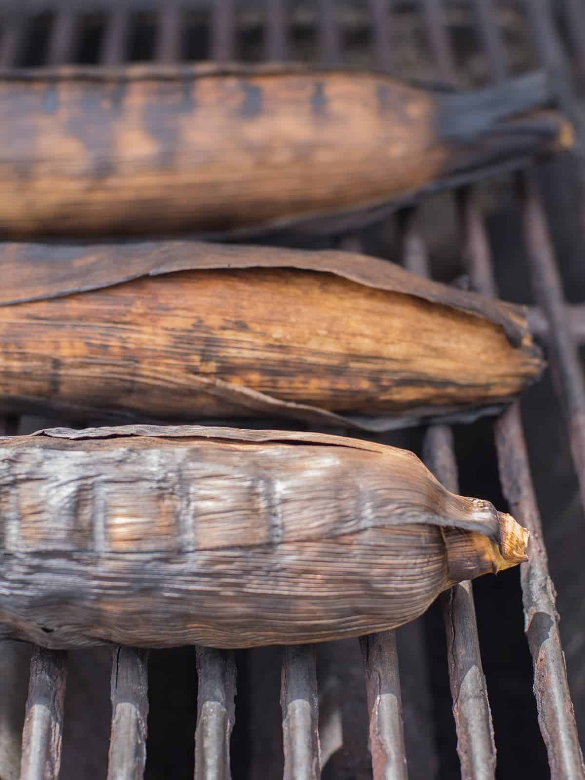 corn on the cob being grilled with the husks on