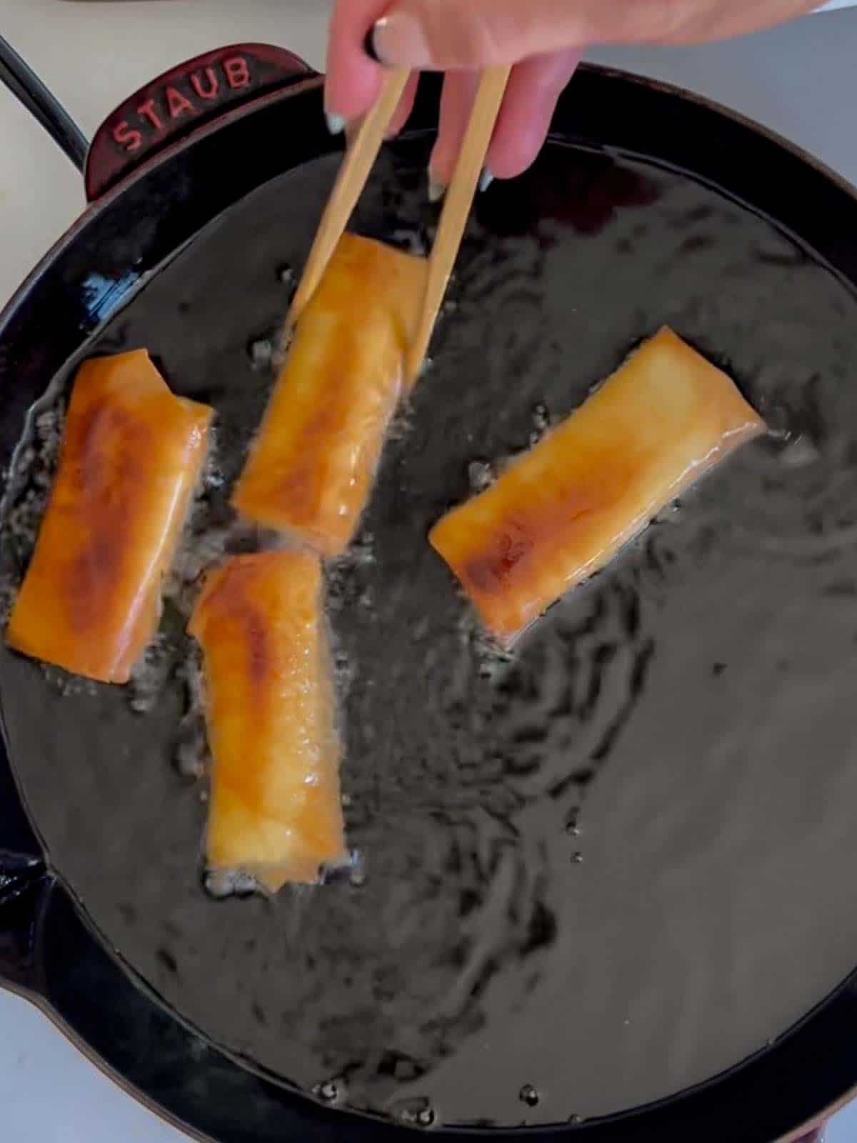 banana lumpia being fried in oil until it's golden brown