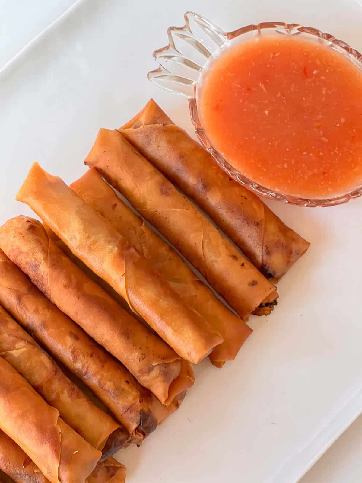 lumpia on a white tray with lumpia dipping sauce