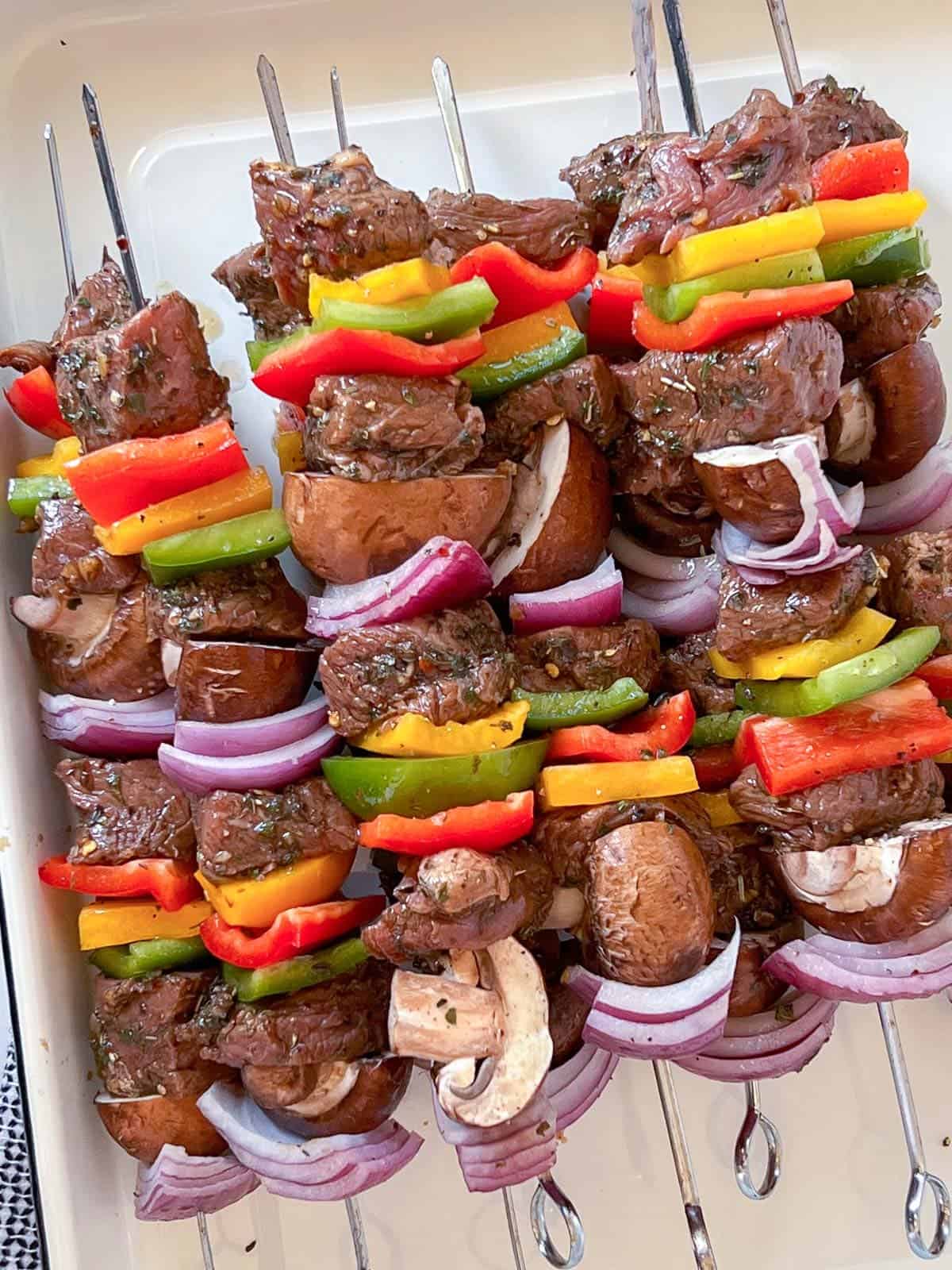 a stack of beef shish kebobs on a whit platter