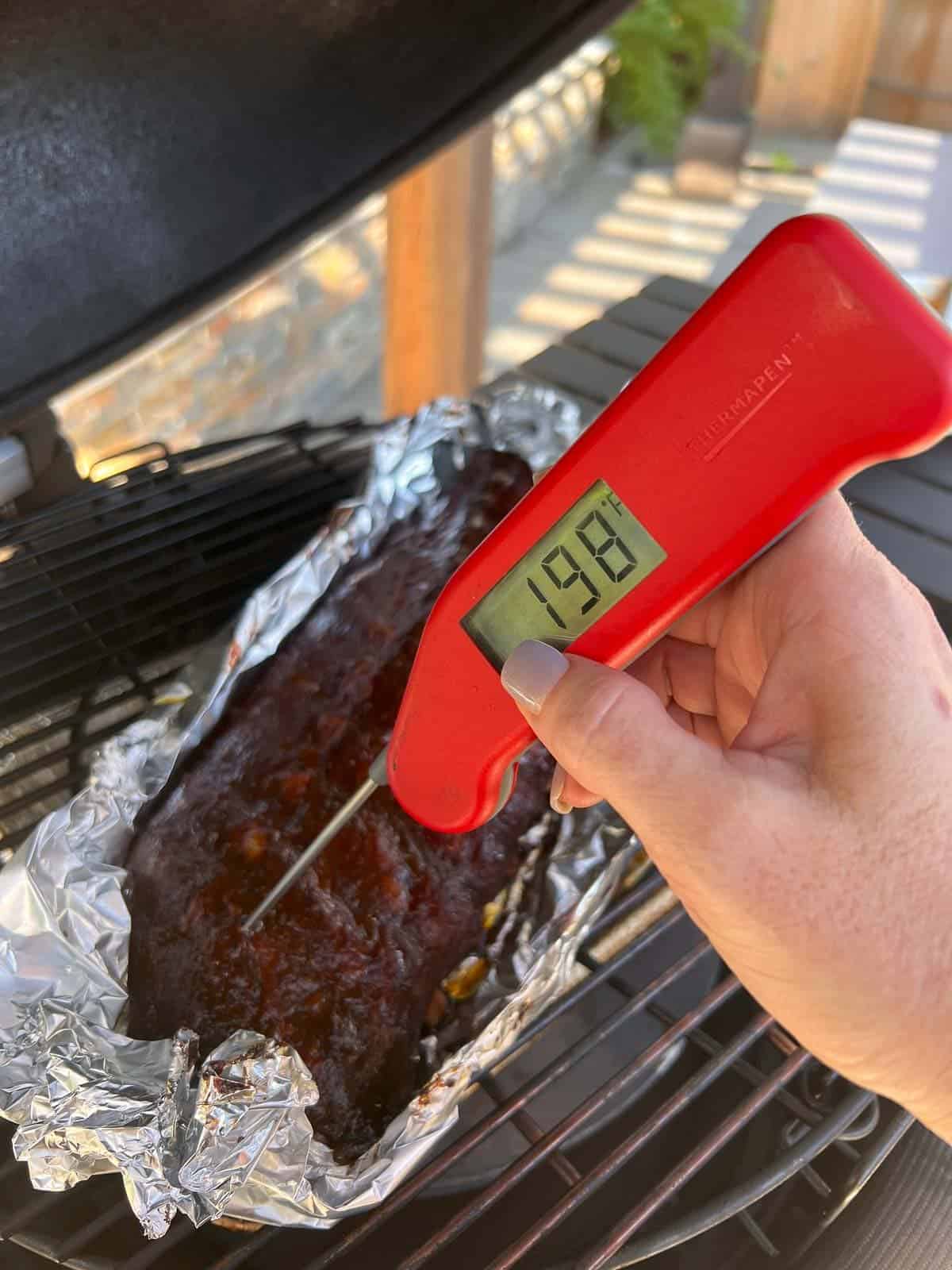 checking the temperature of smoked ribs with a probe thermometer