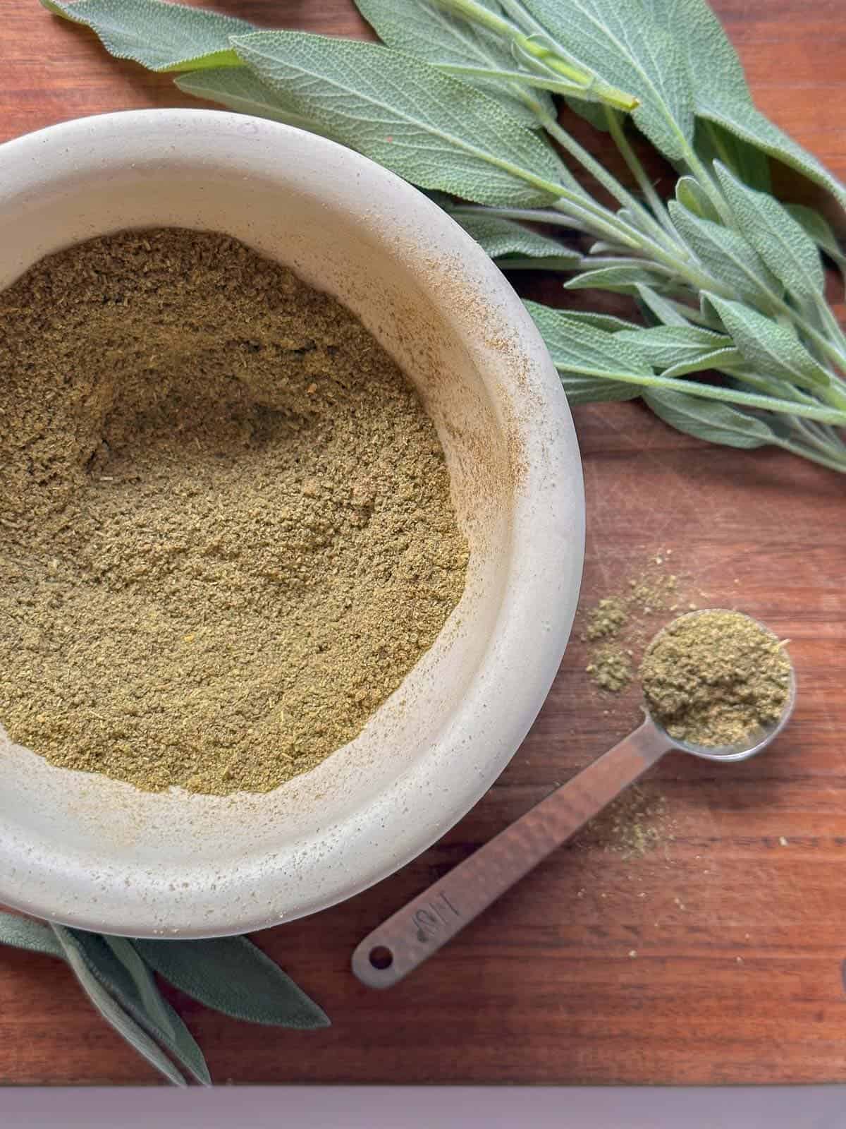 poutlry seasoning recipes in a mortar with fresh sage next to it.